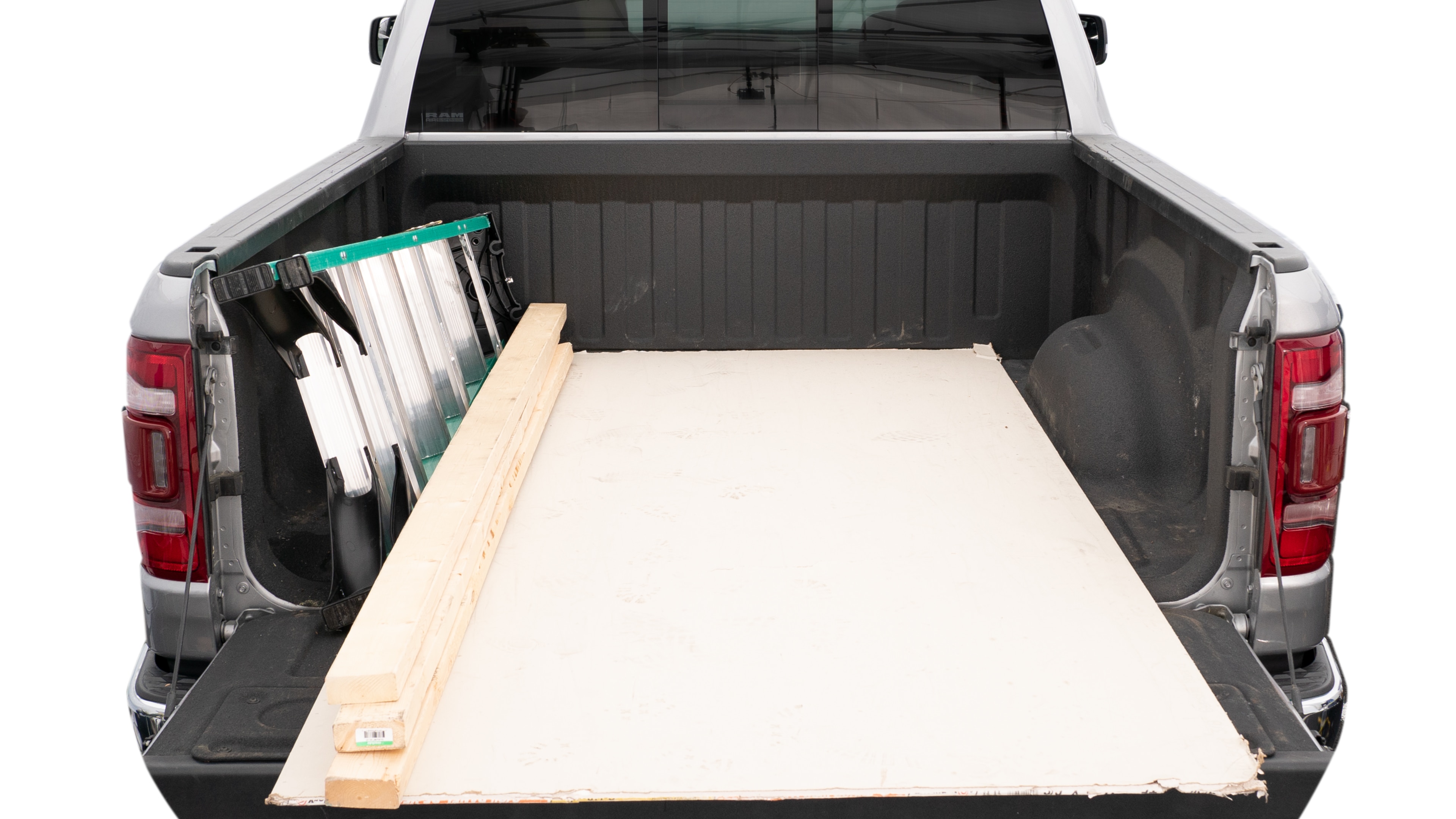 The trunk area is open giving a full view of the trunk area. A ladder, three 2 by 4 framing studs, two tool boxes and a 4 by 8 drywall sheet are placed inside. 