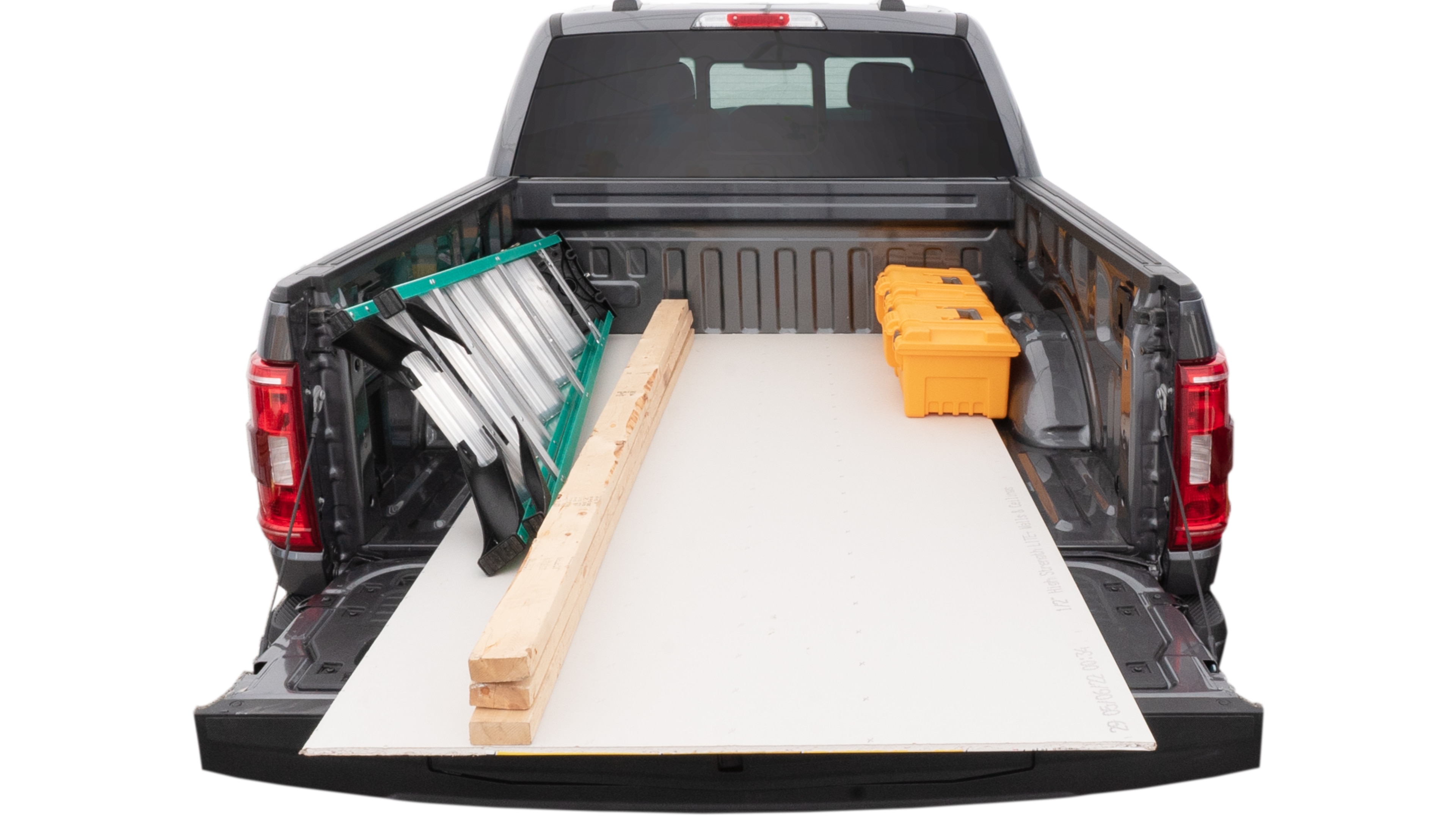 The trunk area is open giving a full view of the trunk area. A ladder, three 2 by 4 framing studs, two tool boxes and a 4 by 8 drywall sheet are placed inside.