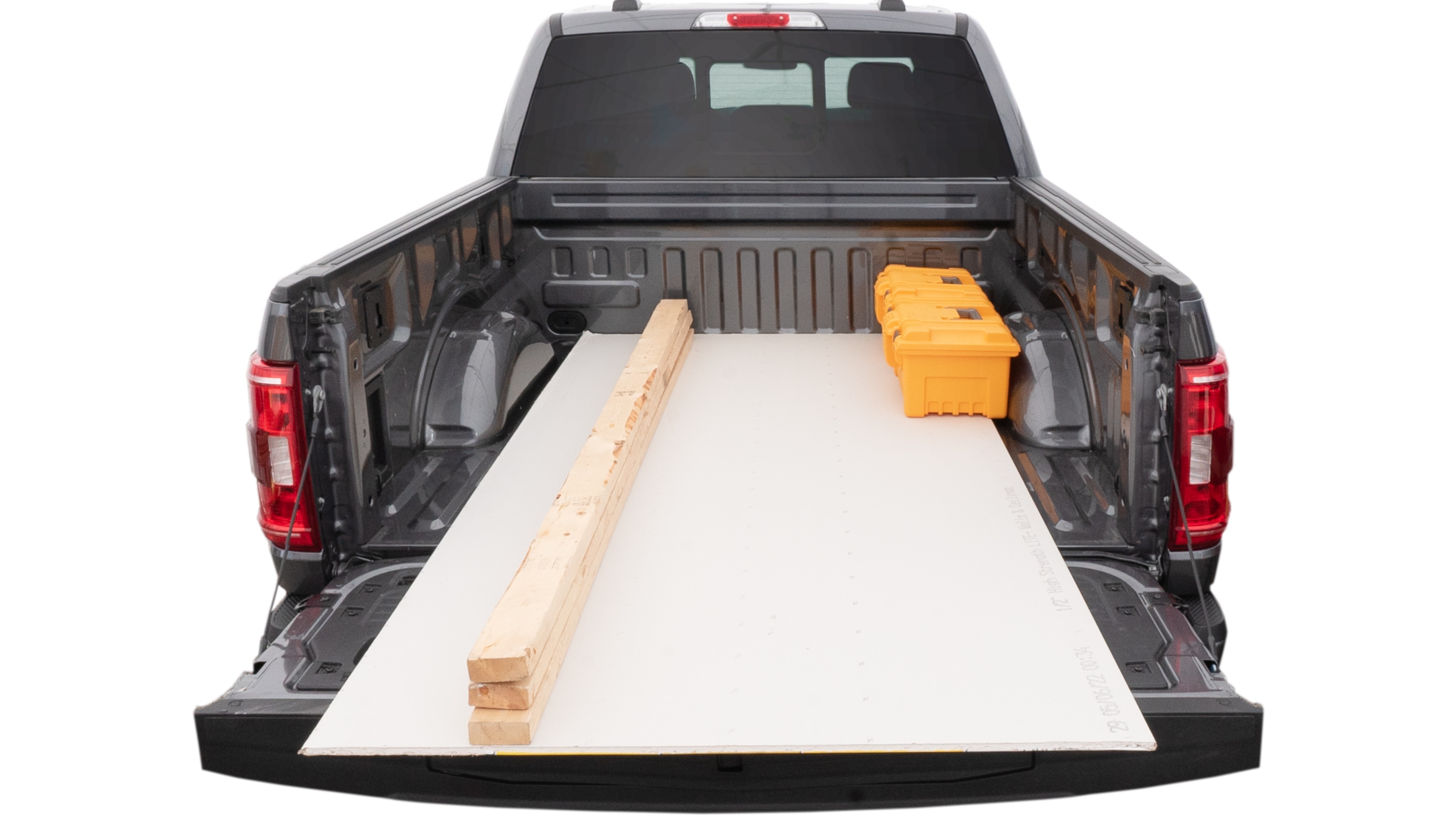 The trunk area is open giving a full view of the trunk area. A ladder, three 2 by 4 framing studs, two tool boxes and a 4 by 8 drywall sheet are placed inside.