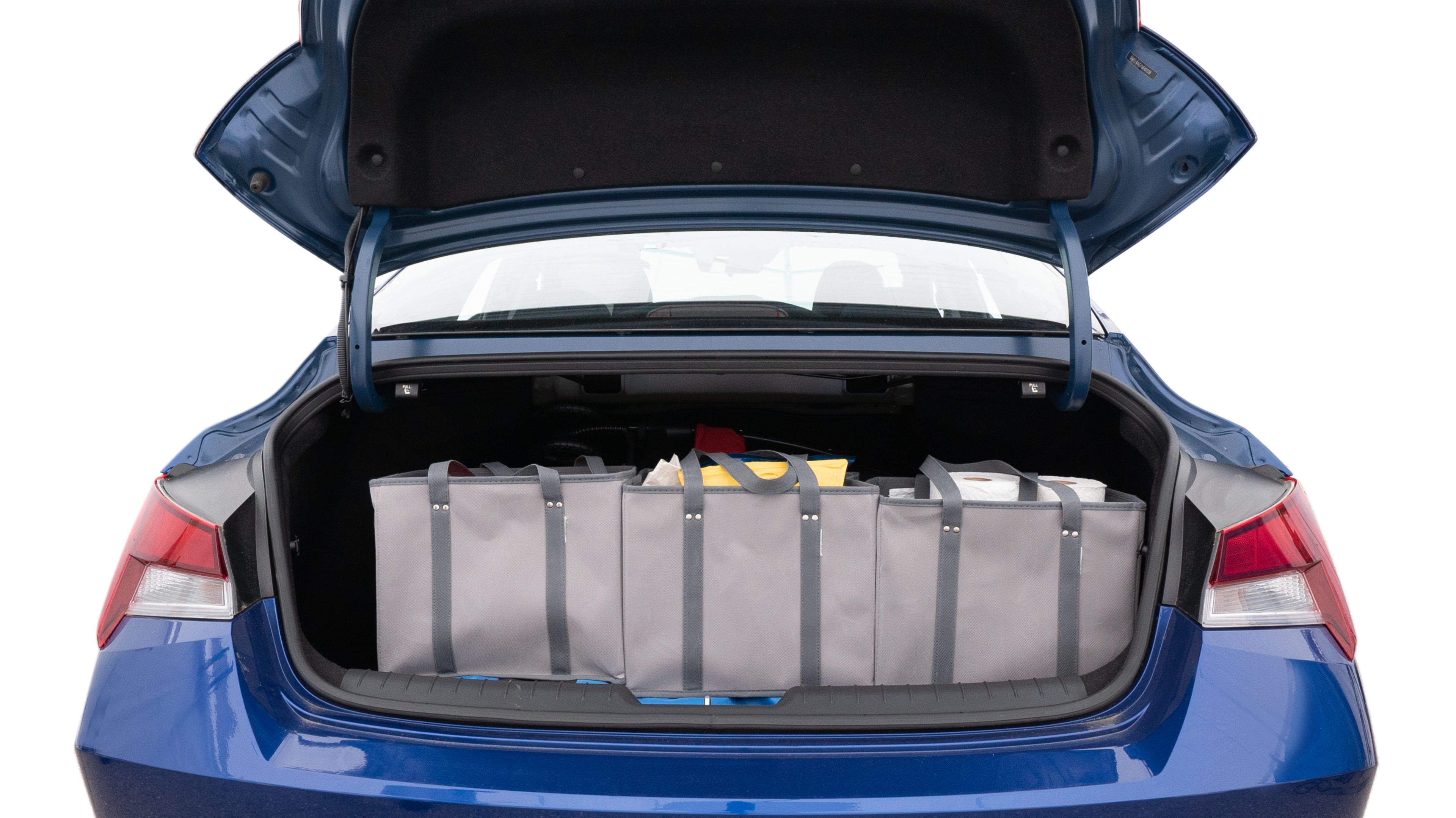 The trunk lid is open showing full view of the trunk. A baby stroller, three grocery carriers, two camping chairs in the carrying bag, and a set of golf clubs are placed inside.