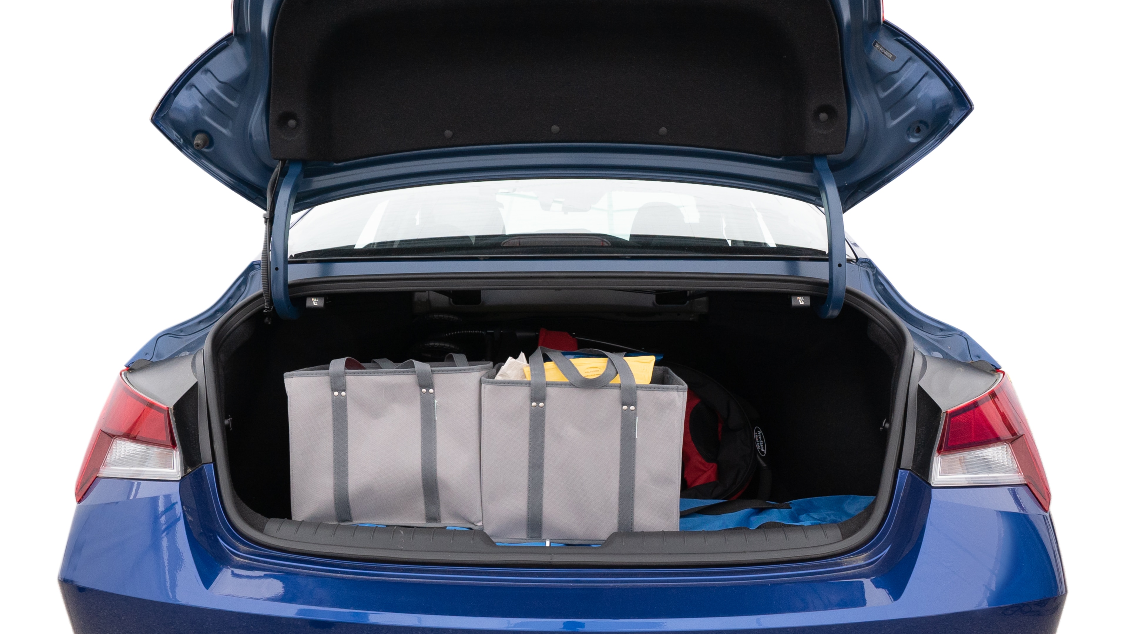The trunk lid is open showing full view of the trunk. A baby stroller, three grocery carriers, two camping chairs in the carrying bag, and a set of golf clubs are placed inside.