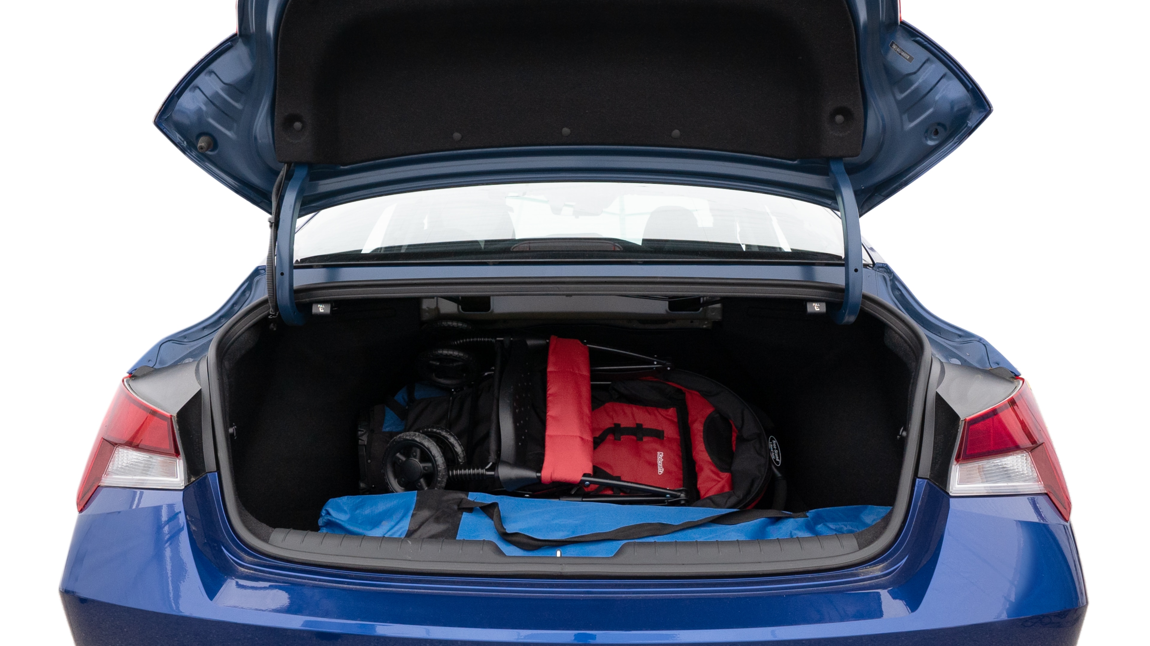 The trunk lid is open showing full view of the trunk. A baby stroller, three grocery carriers, two camping chairs in the carrying bag, and a set of golf clubs are placed inside.