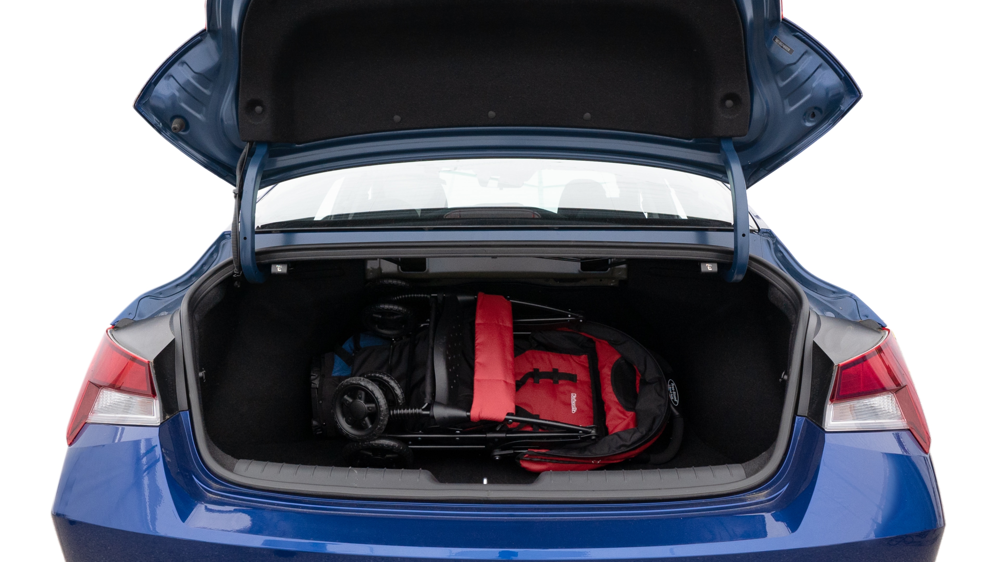 The trunk lid is open showing full view of the trunk. A baby stroller, three grocery carriers, two camping chairs in the carrying bag, and a set of golf clubs are placed inside.