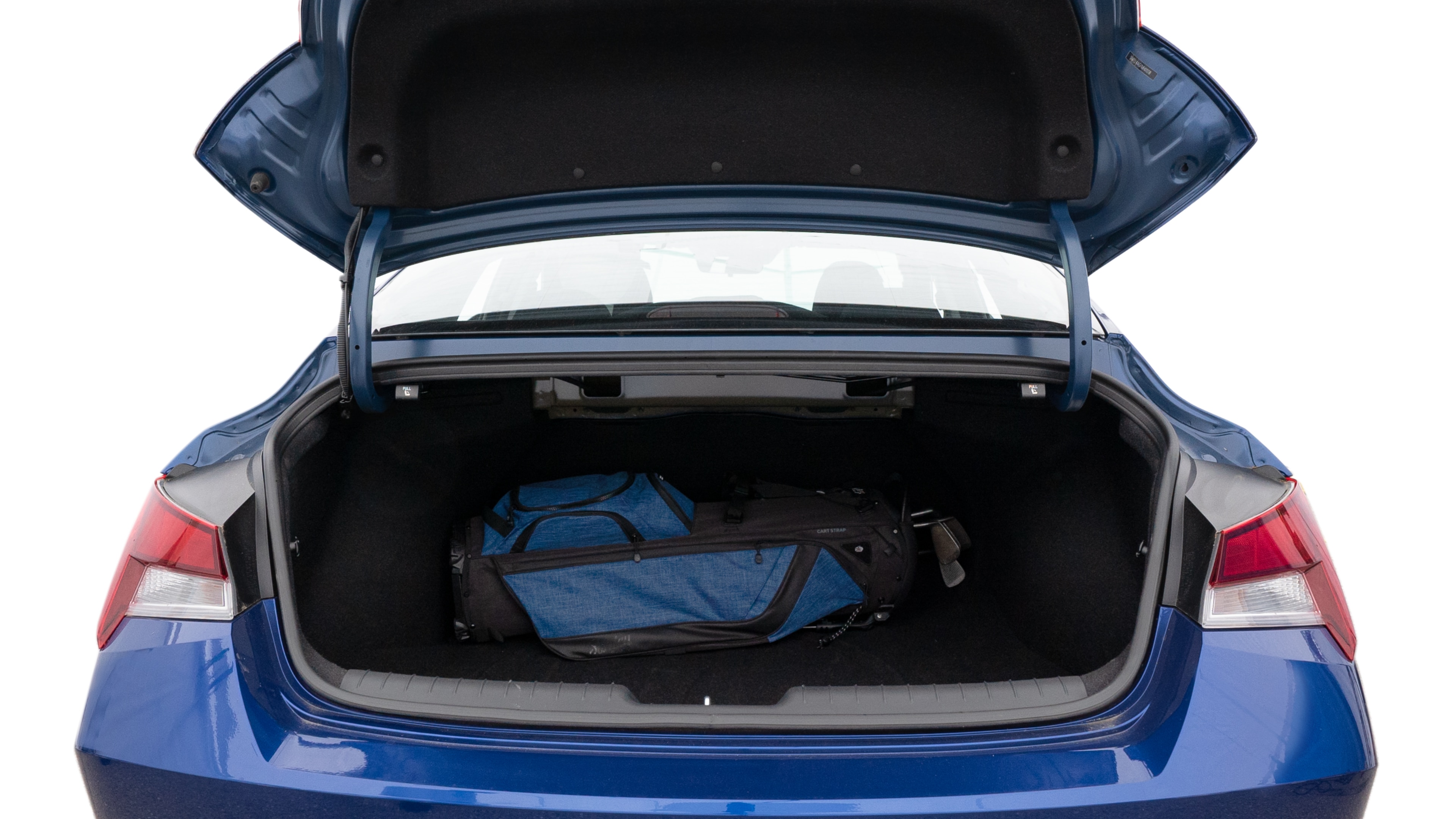 The trunk lid is open showing full view of the trunk. A baby stroller, three grocery carriers, two camping chairs in the carrying bag, and a set of golf clubs are placed inside.