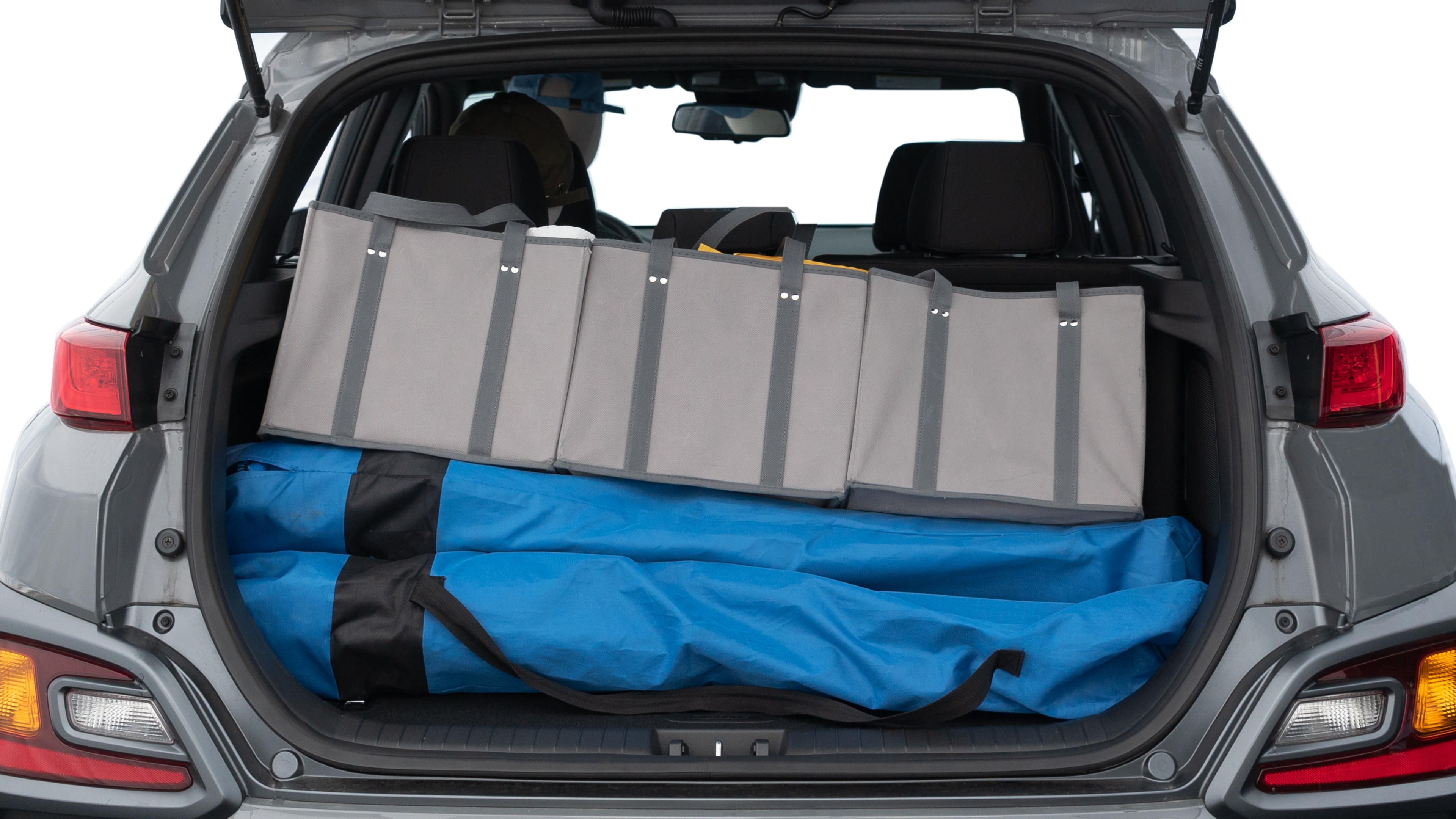 The trunk lid is open showing full view of the trunk. A baby stroller, three grocery carriers, two camping chairs in the carrying bag, and a set of golf clubs are placed inside.