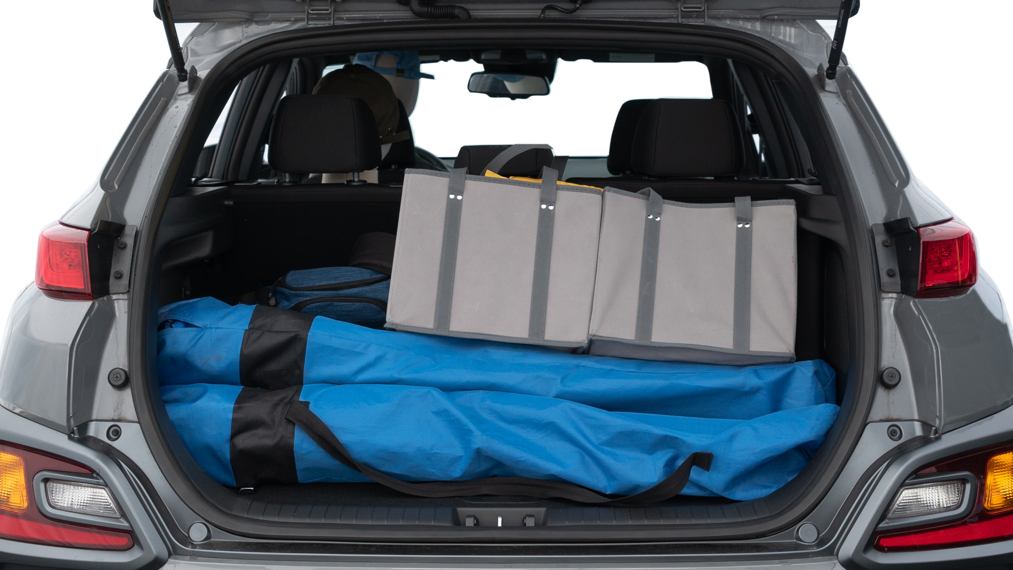 The trunk lid is open showing full view of the trunk. A baby stroller, three grocery carriers, two camping chairs in the carrying bag, and a set of golf clubs are placed inside.