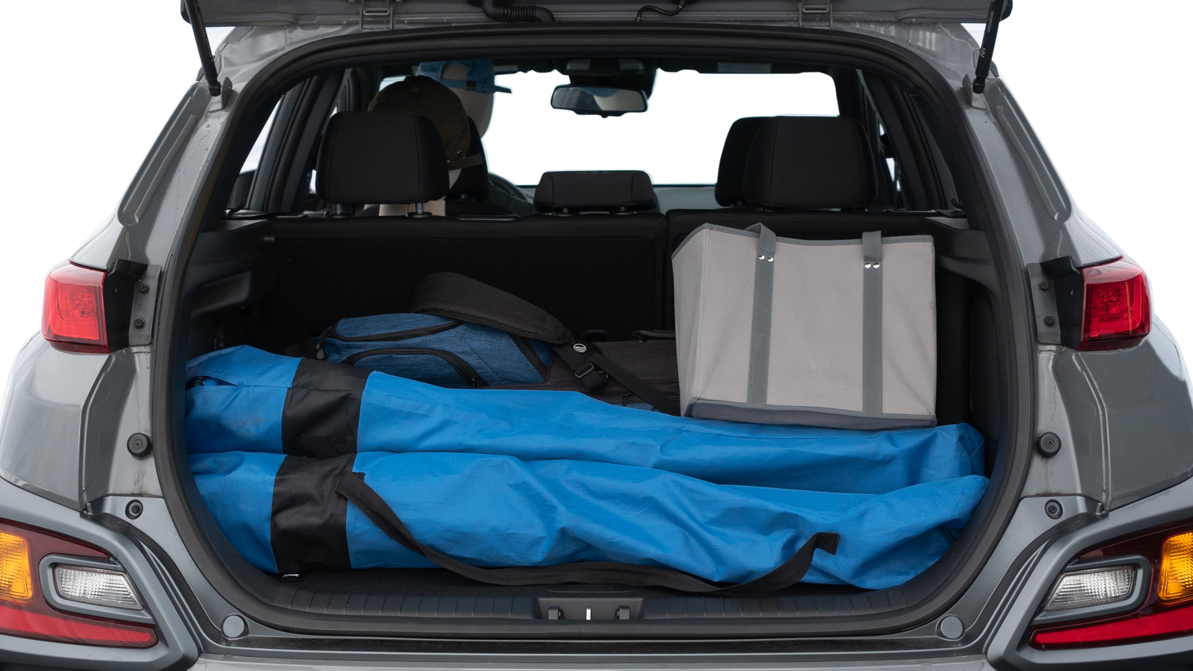 The trunk lid is open showing full view of the trunk. A baby stroller, three grocery carriers, two camping chairs in the carrying bag, and a set of golf clubs are placed inside.