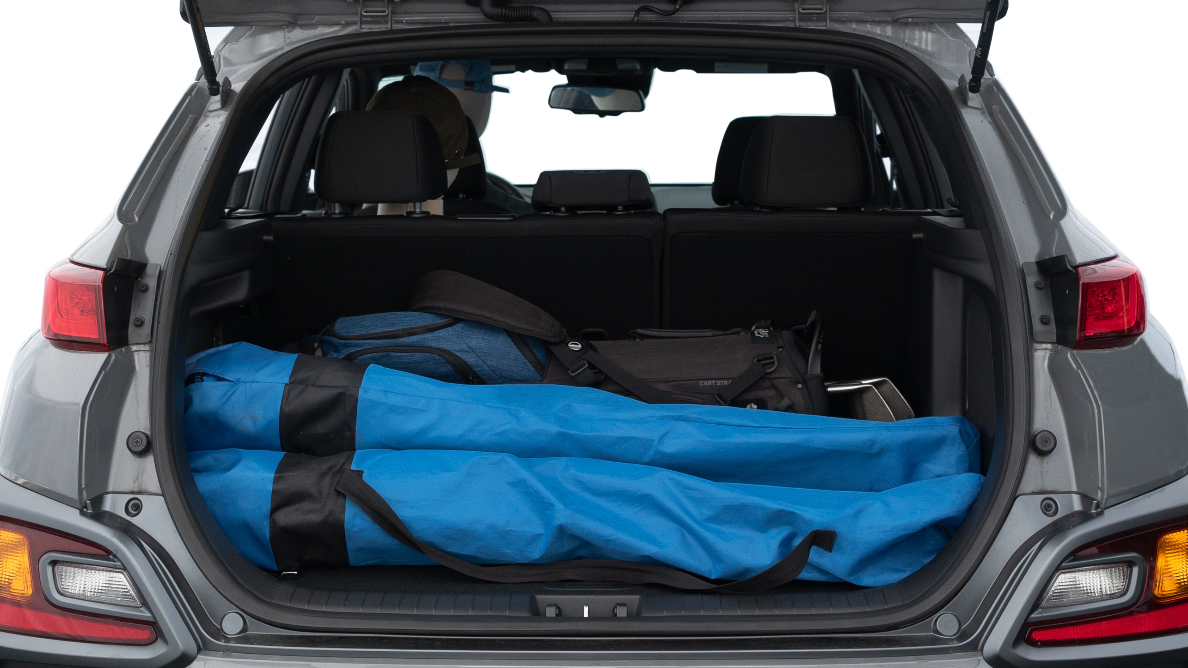 The trunk lid is open showing full view of the trunk. A baby stroller, three grocery carriers, two camping chairs in the carrying bag, and a set of golf clubs are placed inside.