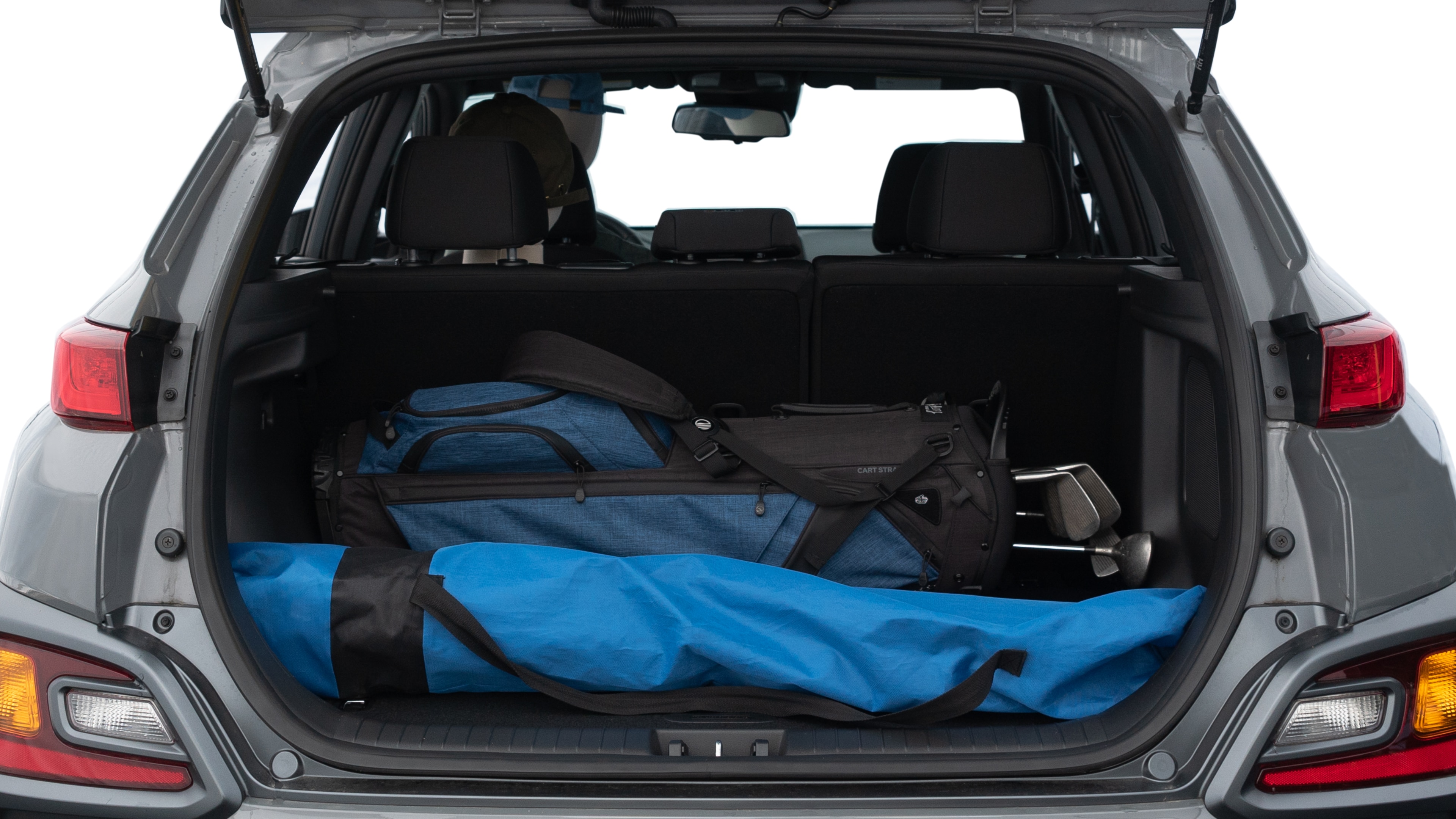 The trunk lid is open showing full view of the trunk. A baby stroller, three grocery carriers, two camping chairs in the carrying bag, and a set of golf clubs are placed inside.