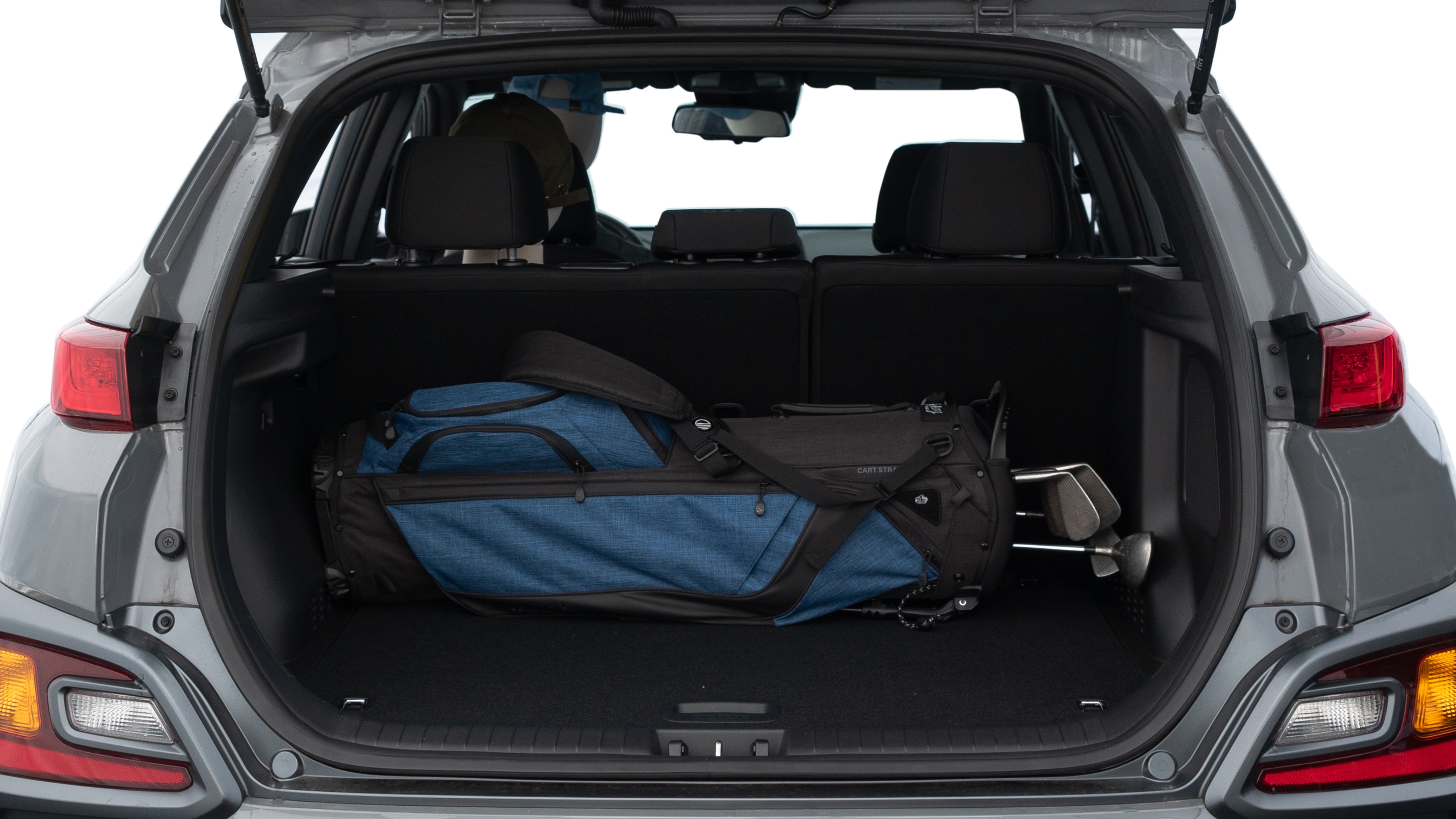 The trunk lid is open showing full view of the trunk. A baby stroller, three grocery carriers, two camping chairs in the carrying bag, and a set of golf clubs are placed inside.