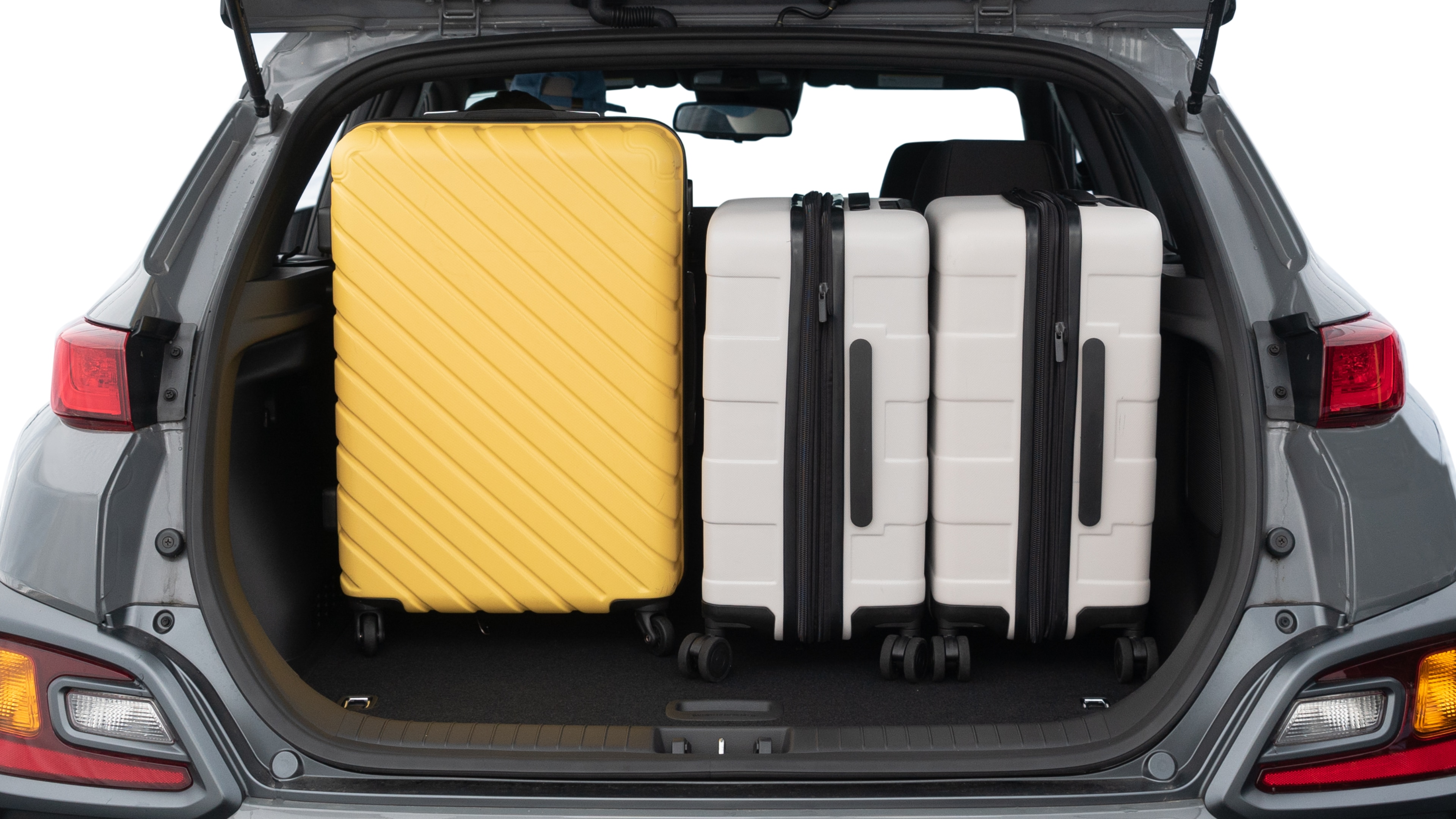 The trunk lid is open, showing full view of the trunk space. One medium and two small suitcases are placed inside.