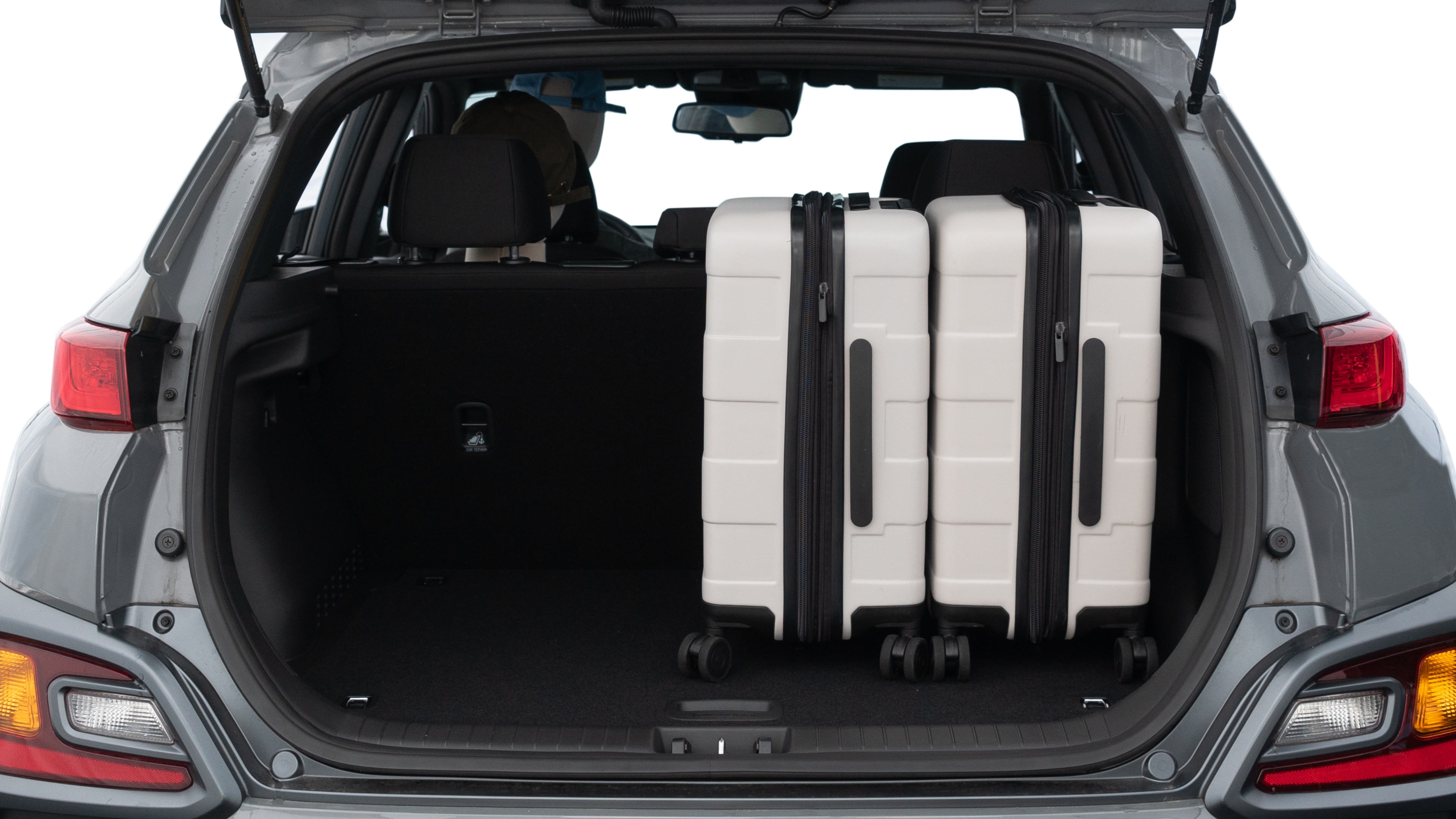The trunk lid is open, showing full view of the trunk space. One medium and two small suitcases are placed inside.