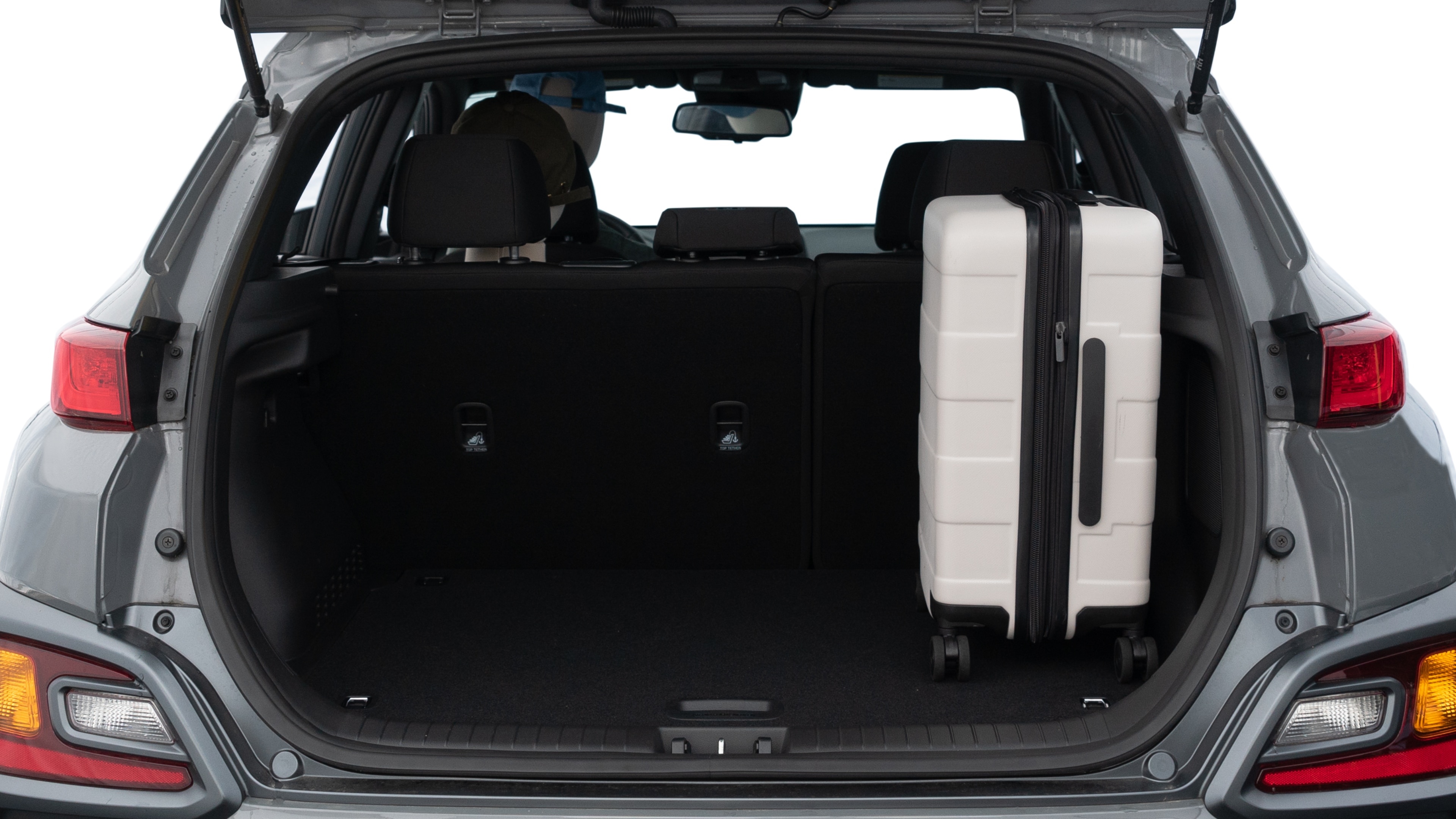 The trunk lid is open, showing full view of the trunk space. One medium and two small suitcases are placed inside.