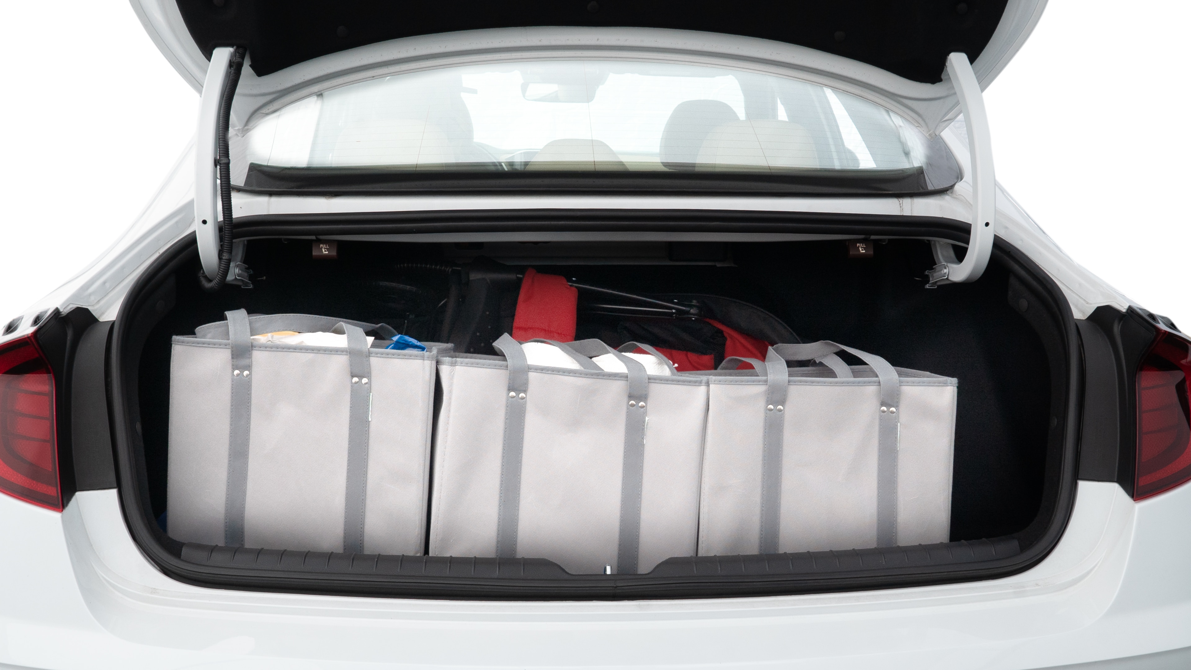 The trunk lid is open showing full view of the trunk. A baby stroller, three grocery carriers, two camping chairs in the carrying bag, and a set of golf clubs are placed inside.