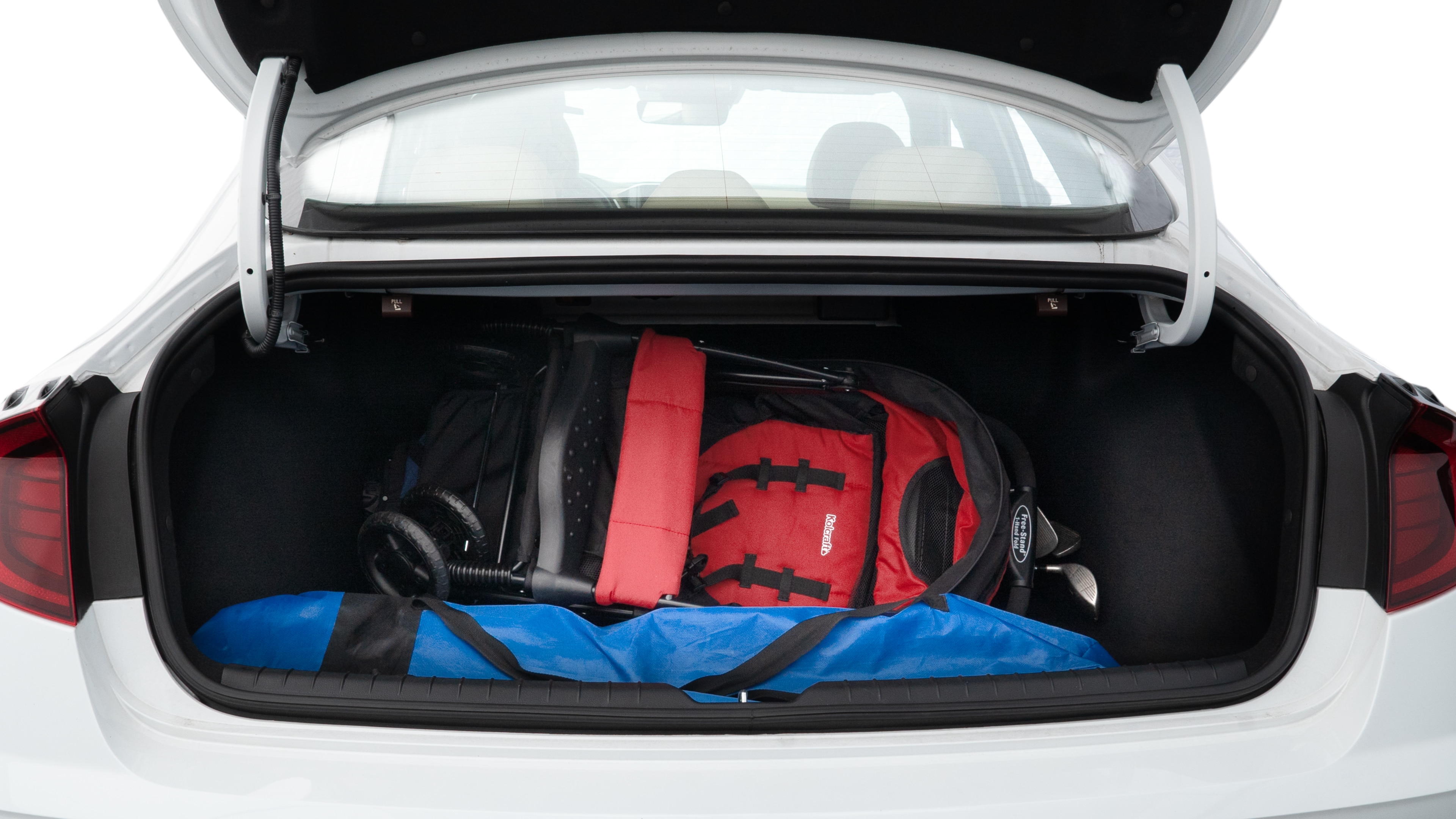 The trunk lid is open showing full view of the trunk. A baby stroller, three grocery carriers, two camping chairs in the carrying bag, and a set of golf clubs are placed inside.