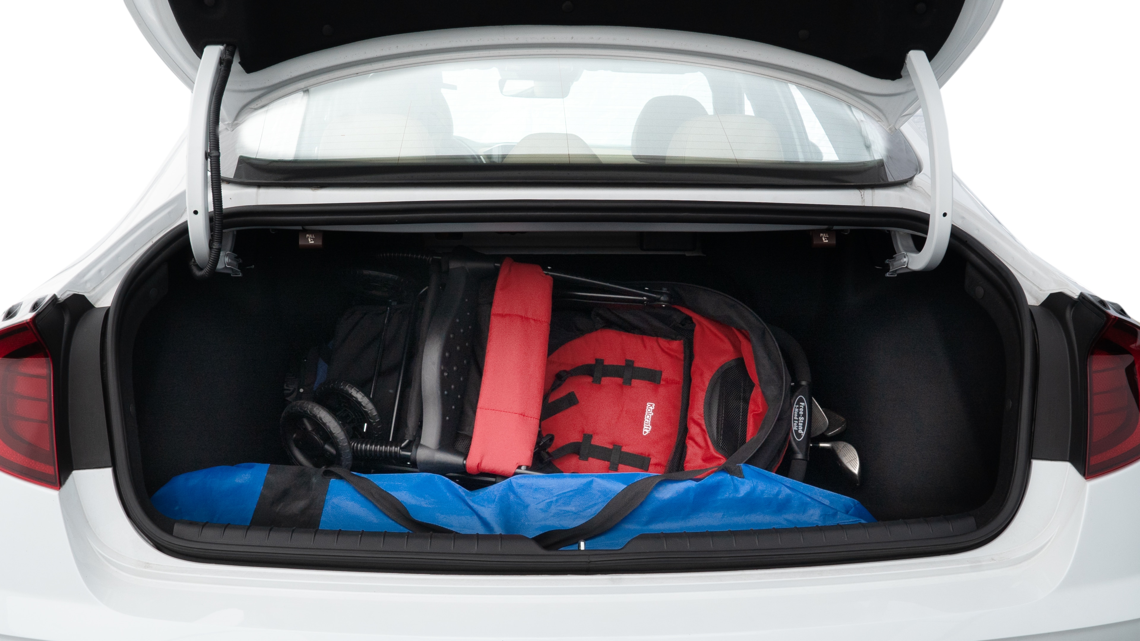 The trunk lid is open showing full view of the trunk. A baby stroller, three grocery carriers, two camping chairs in the carrying bag, and a set of golf clubs are placed inside.