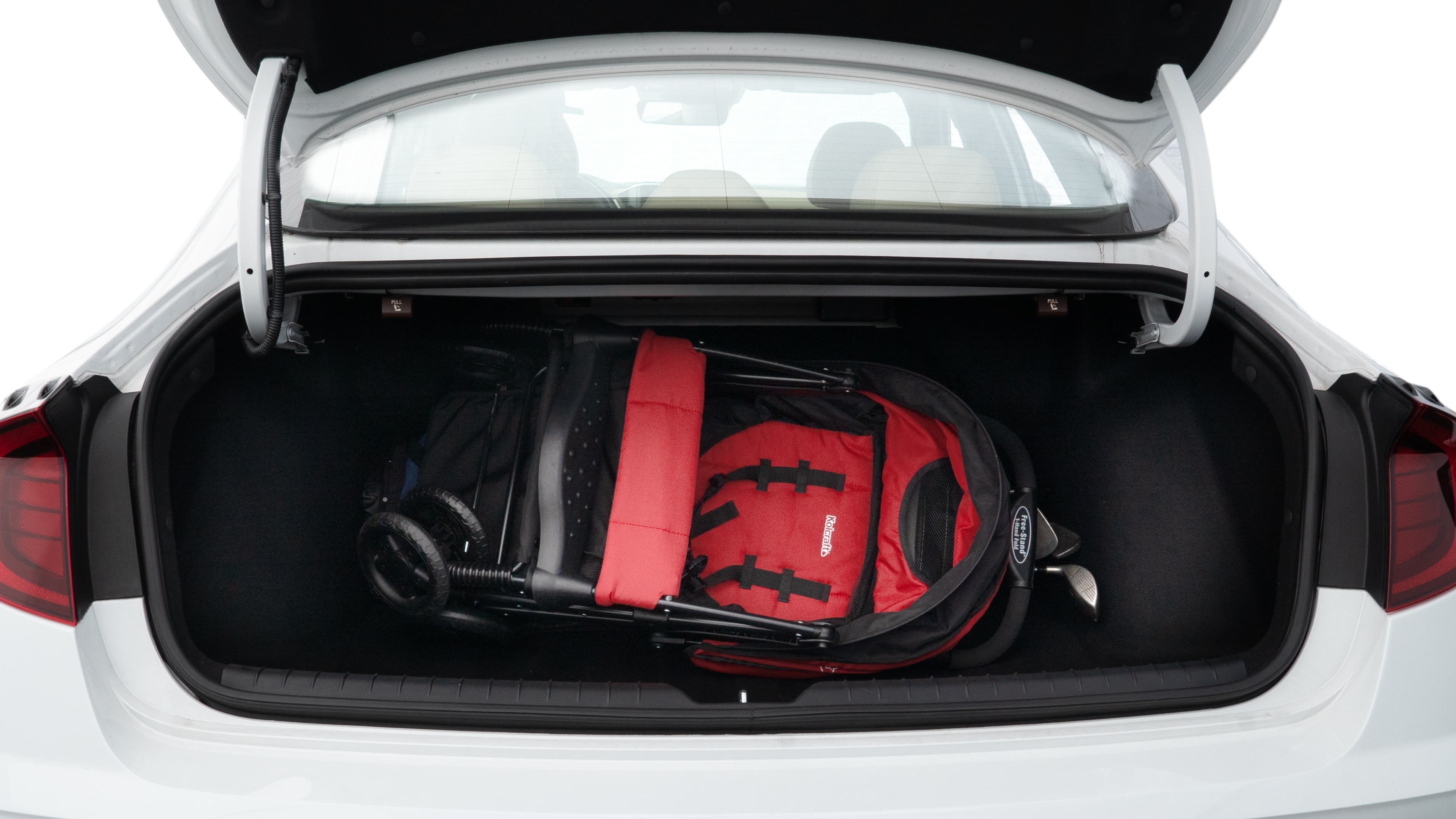The trunk lid is open showing full view of the trunk. A baby stroller, three grocery carriers, two camping chairs in the carrying bag, and a set of golf clubs are placed inside.