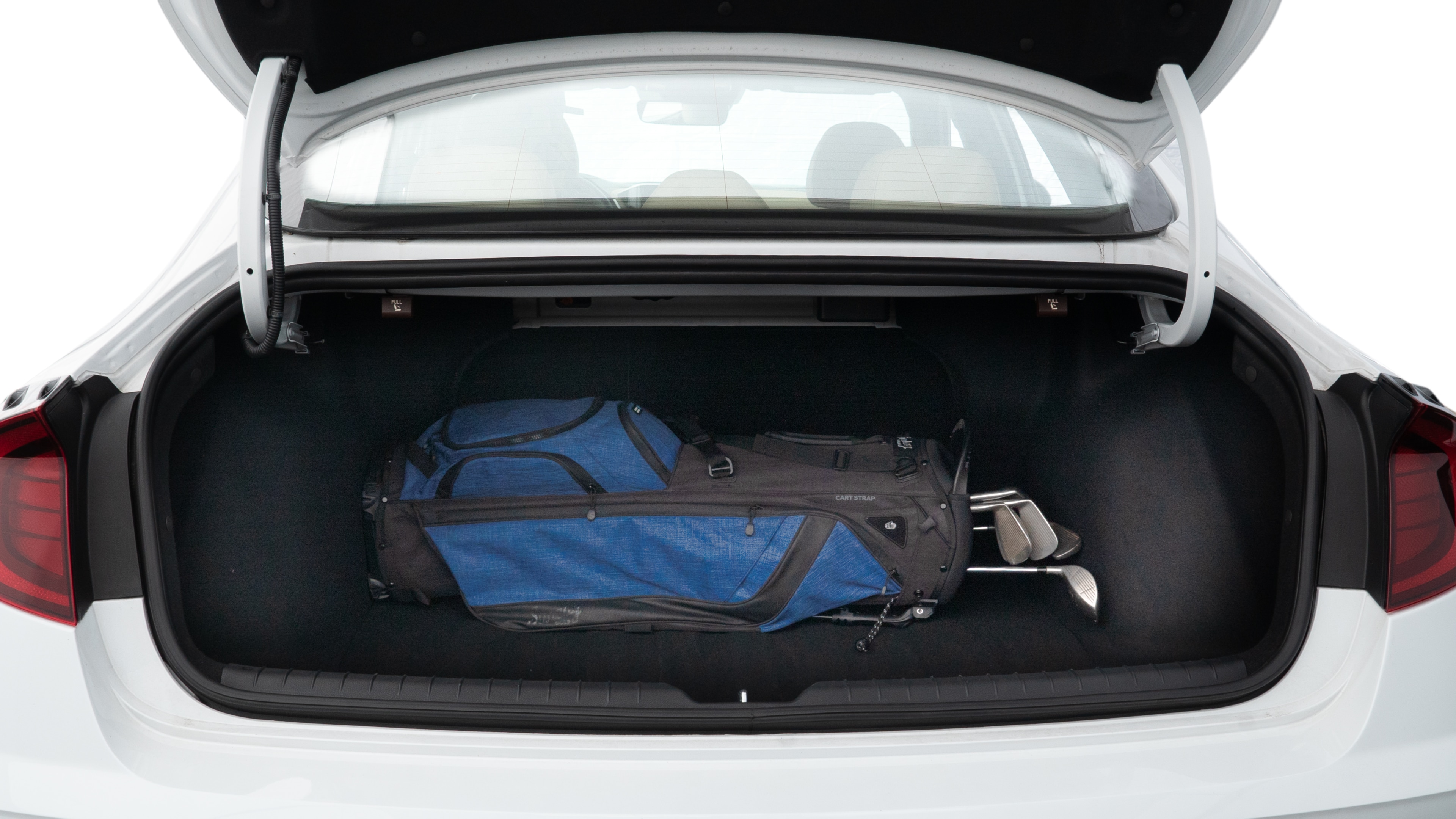 The trunk lid is open showing full view of the trunk. A baby stroller, three grocery carriers, two camping chairs in the carrying bag, and a set of golf clubs are placed inside.