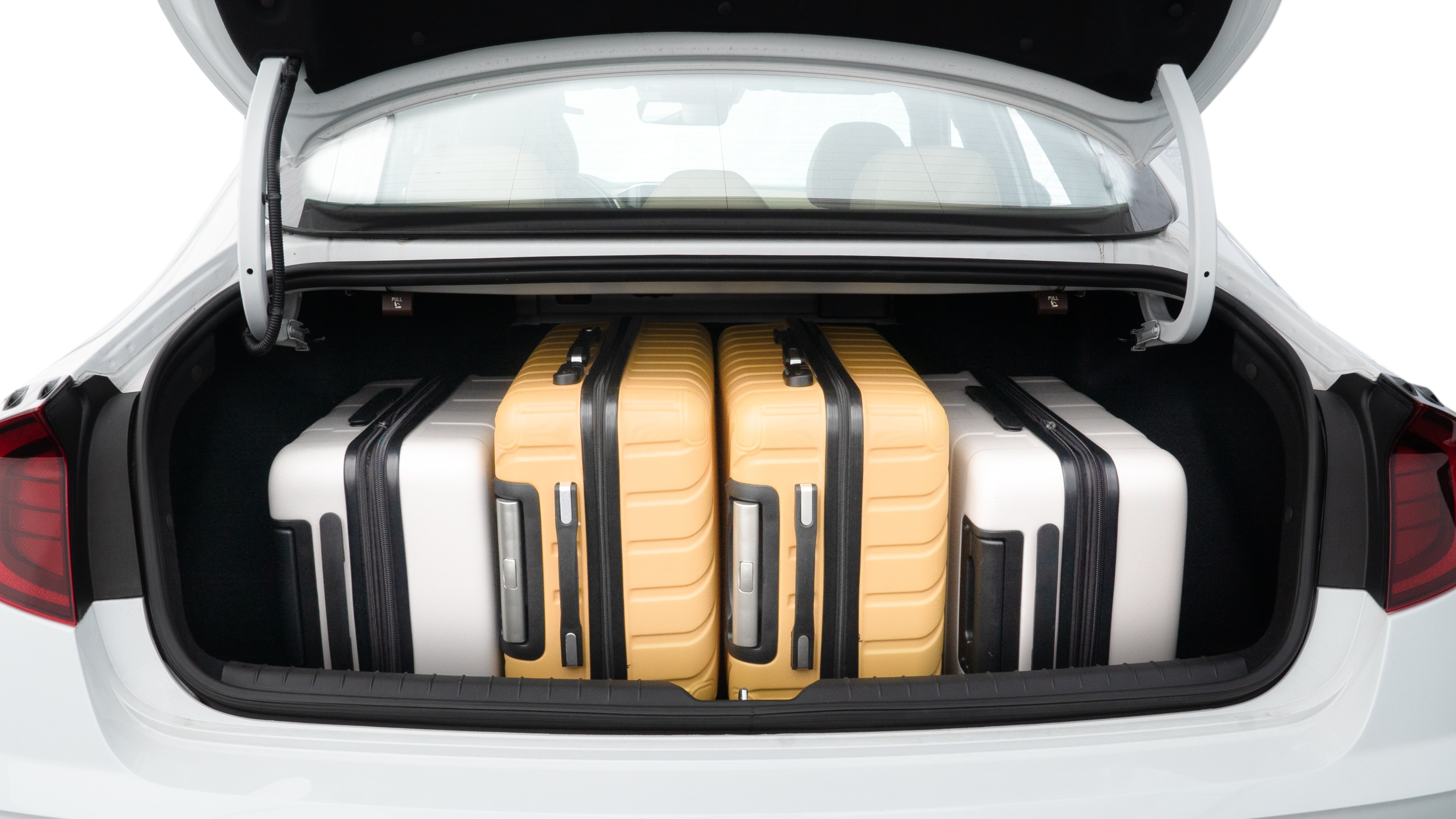 The trunk lid is open, showing full view of the trunk space. Two medium and two small suitcases are placed inside.
