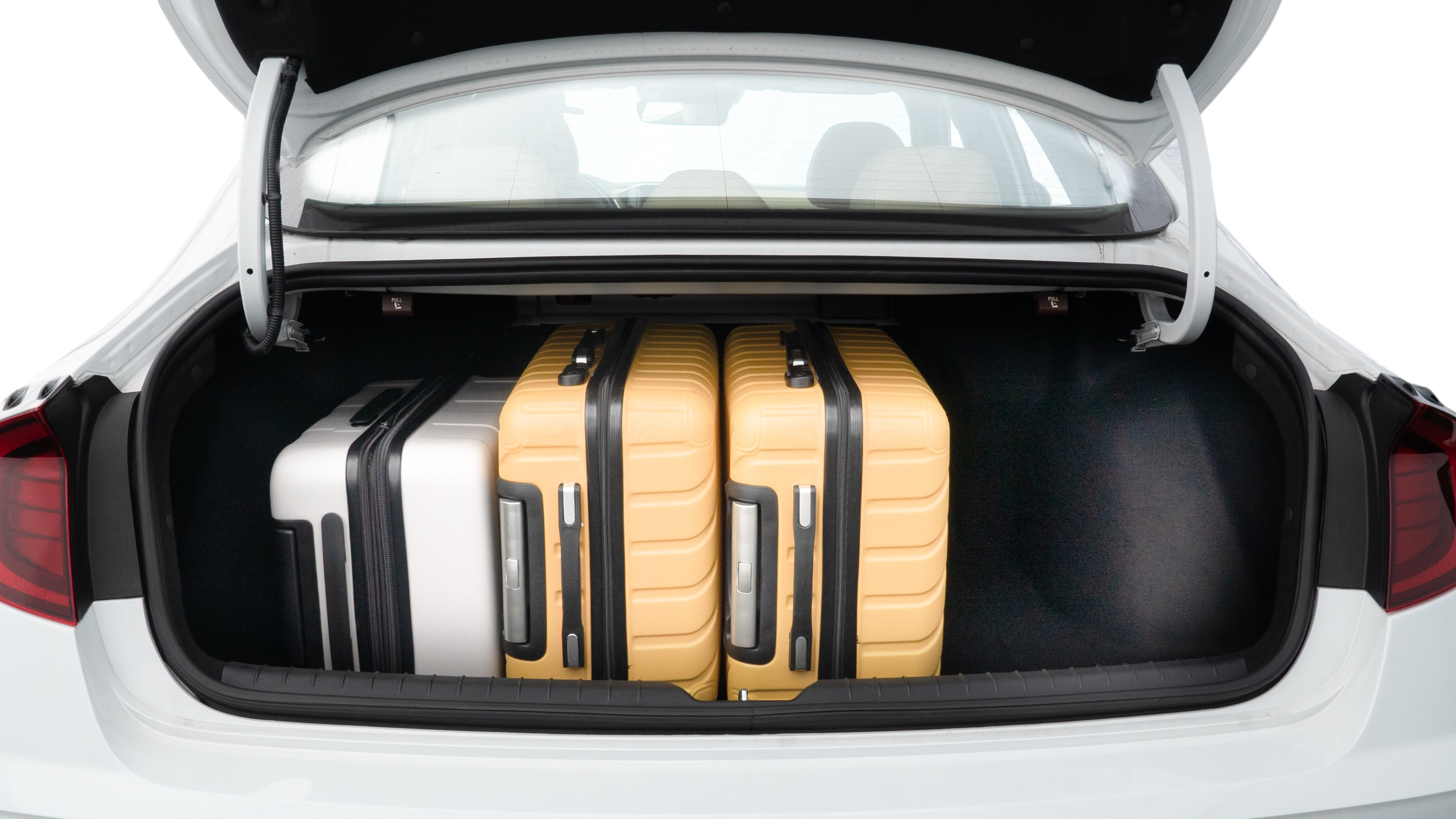 The trunk lid is open, showing full view of the trunk space. Two medium and two small suitcases are placed inside.