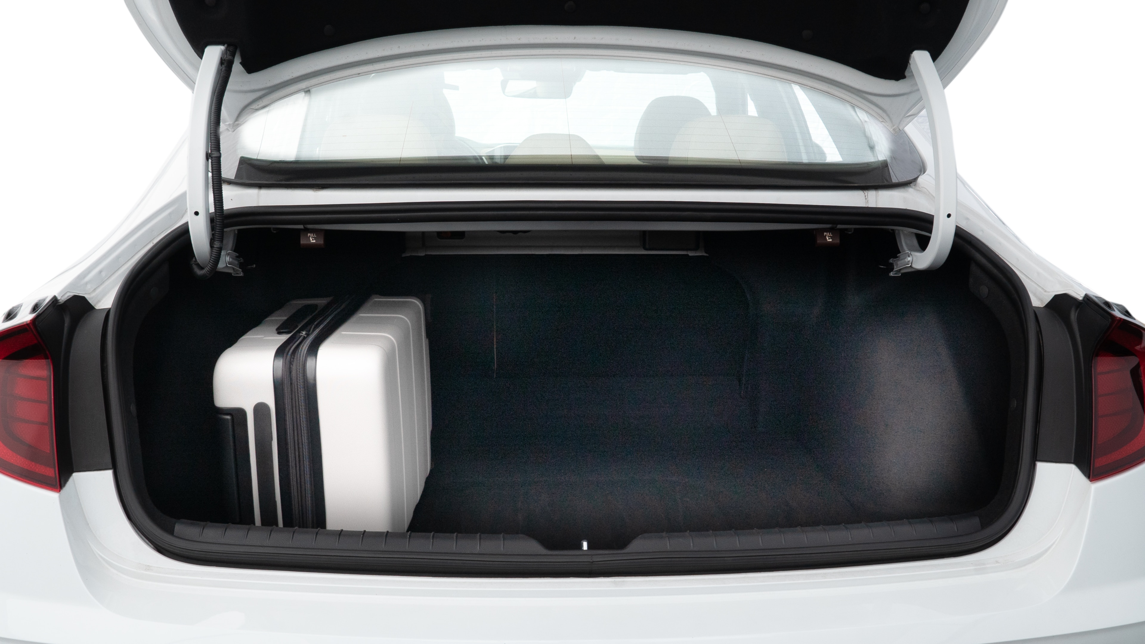 The trunk lid is open, showing full view of the trunk space. Two medium and two small suitcases are placed inside.