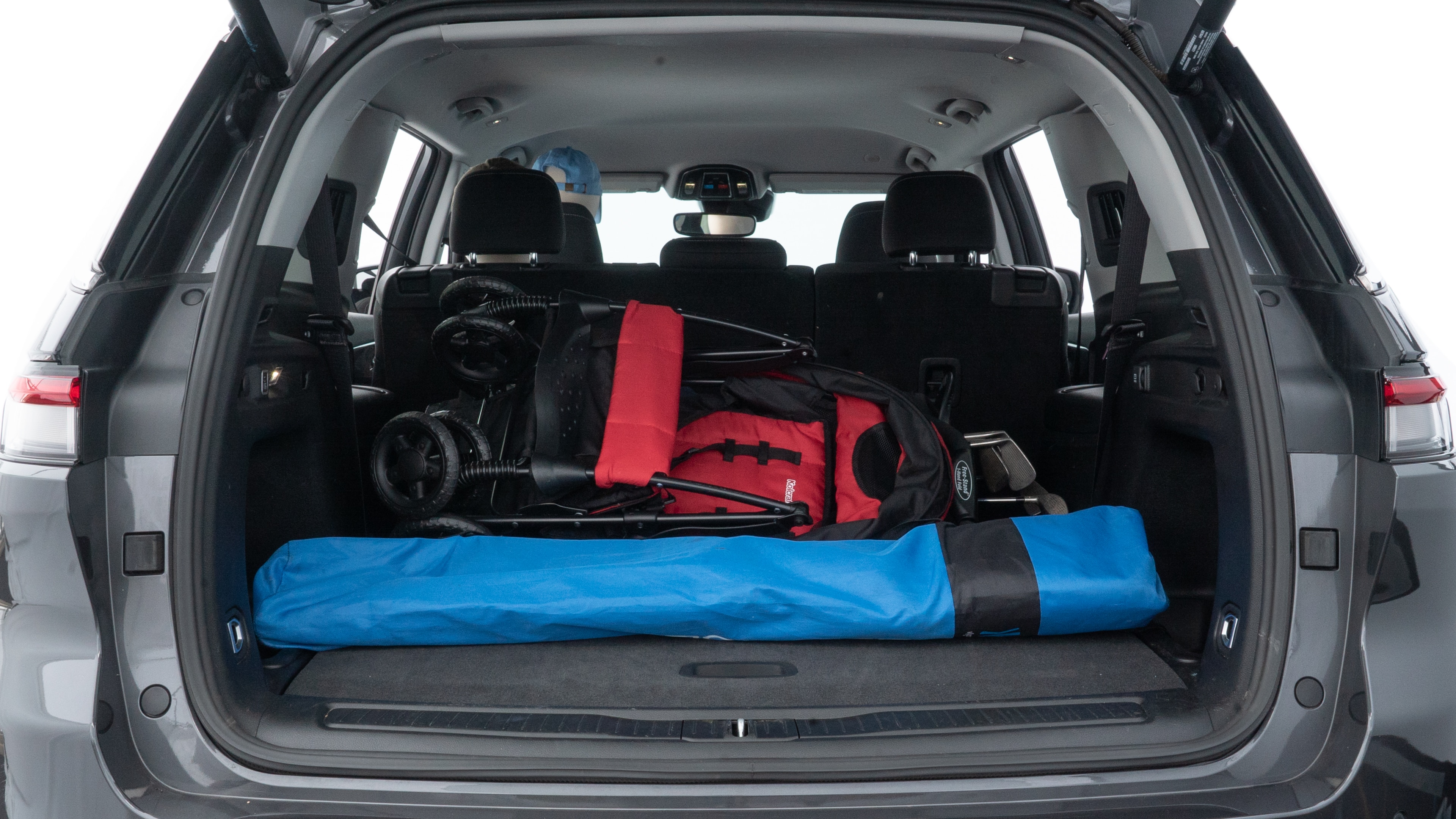 The trunk lid is open showing full view of the trunk. A baby stroller, three grocery carriers, two camping chairs in the carrying bag, and a set of golf clubs are placed inside.