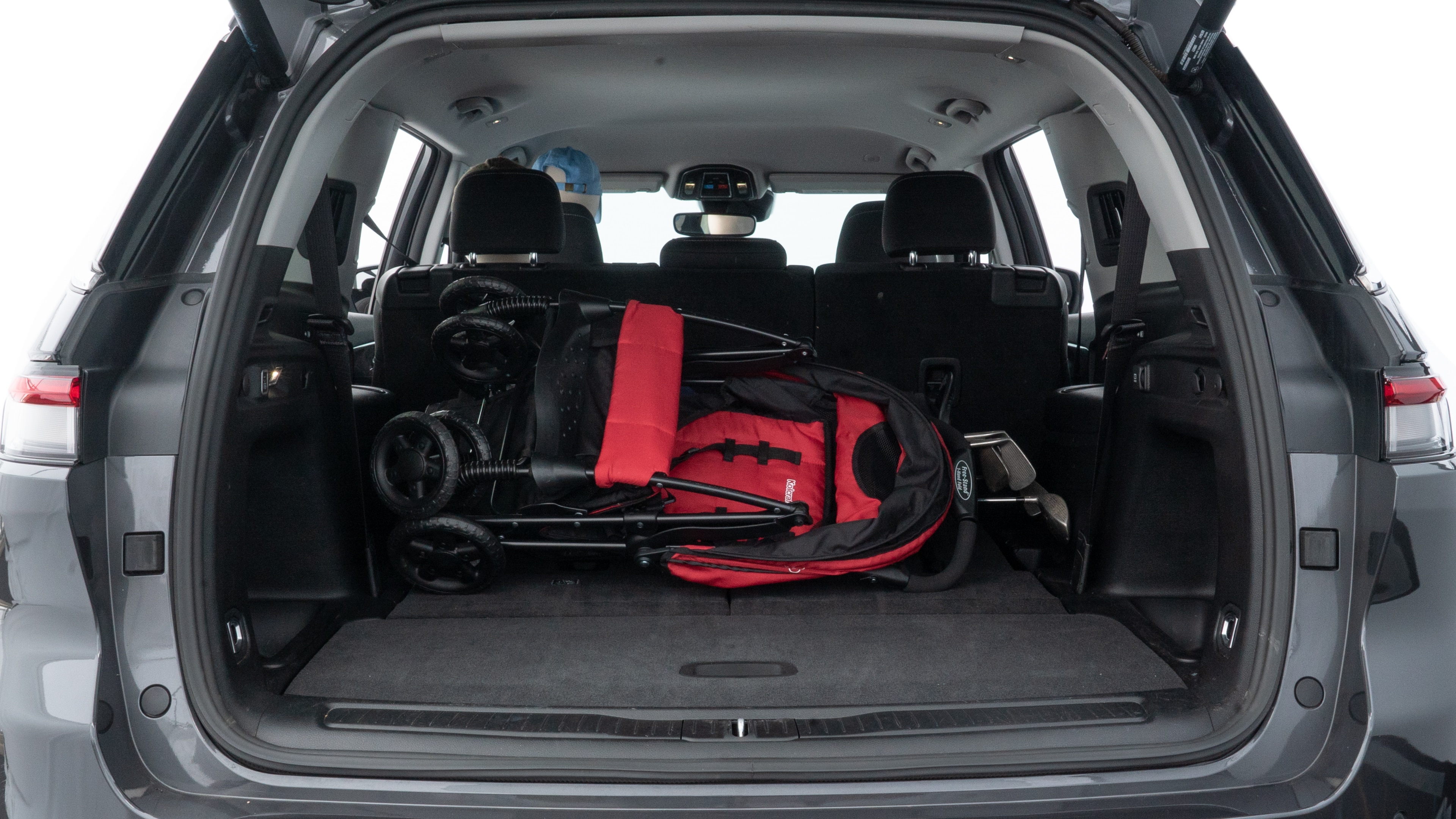 The trunk lid is open showing full view of the trunk. A baby stroller, three grocery carriers, two camping chairs in the carrying bag, and a set of golf clubs are placed inside.