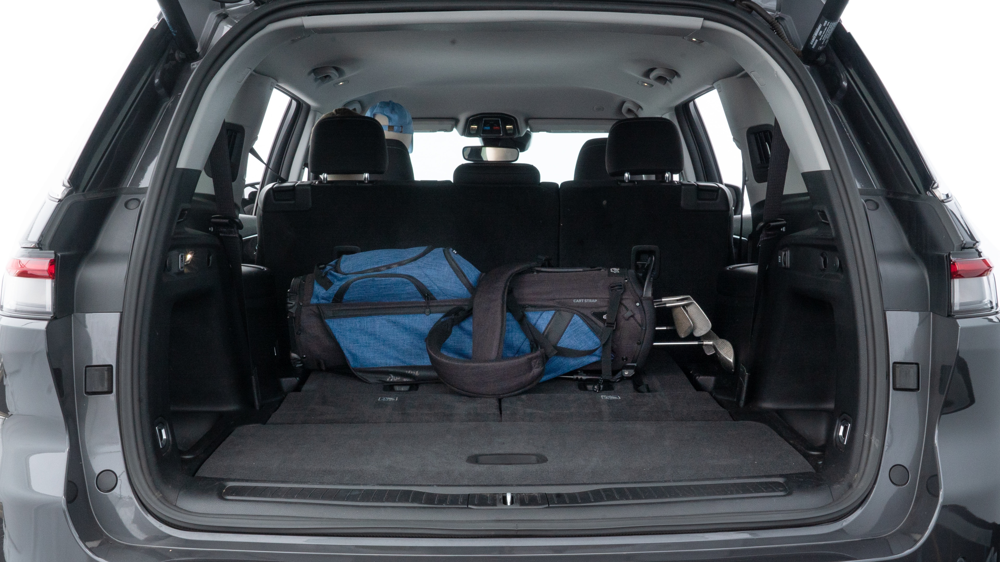 The trunk lid is open showing full view of the trunk. A baby stroller, three grocery carriers, two camping chairs in the carrying bag, and a set of golf clubs are placed inside.