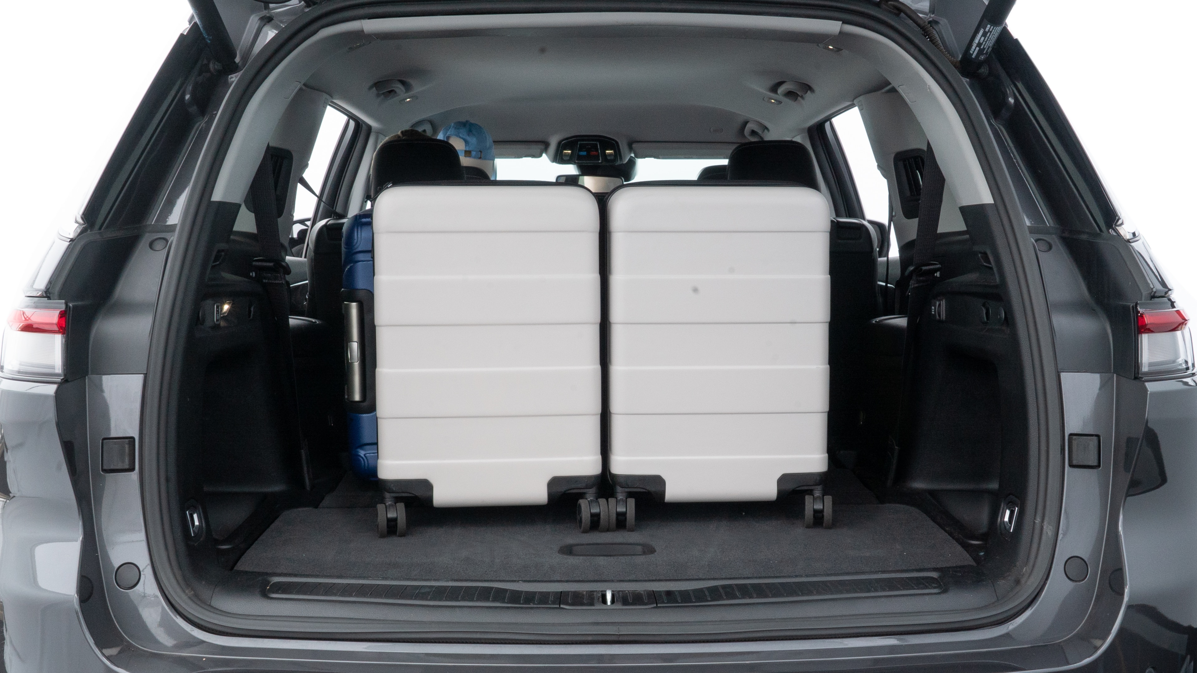 The trunk lid is open, showing full view of the trunk space. One large, two medium, and two small suitcases are placed inside.