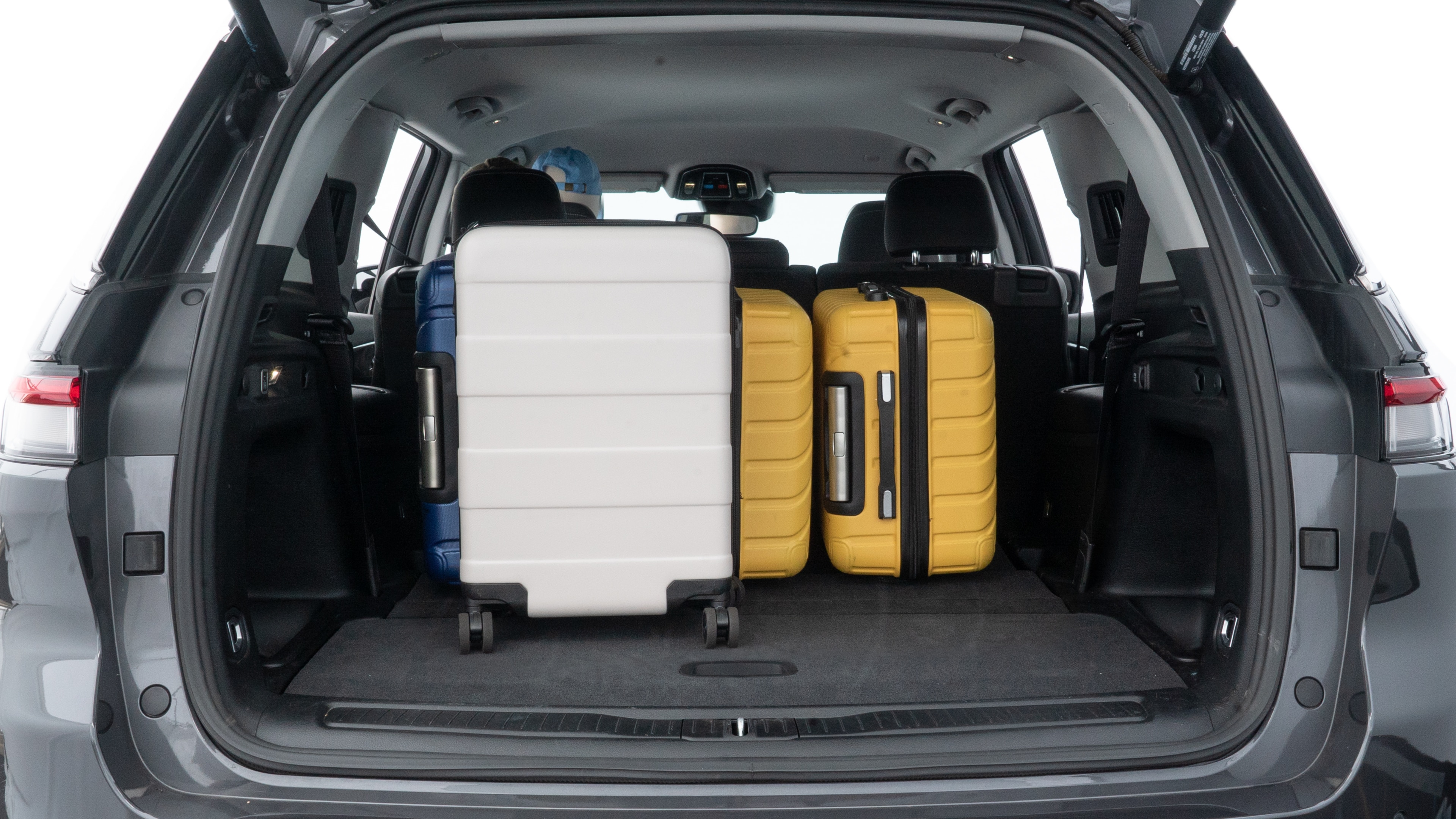 The trunk lid is open, showing full view of the trunk space. One large, two medium, and two small suitcases are placed inside.