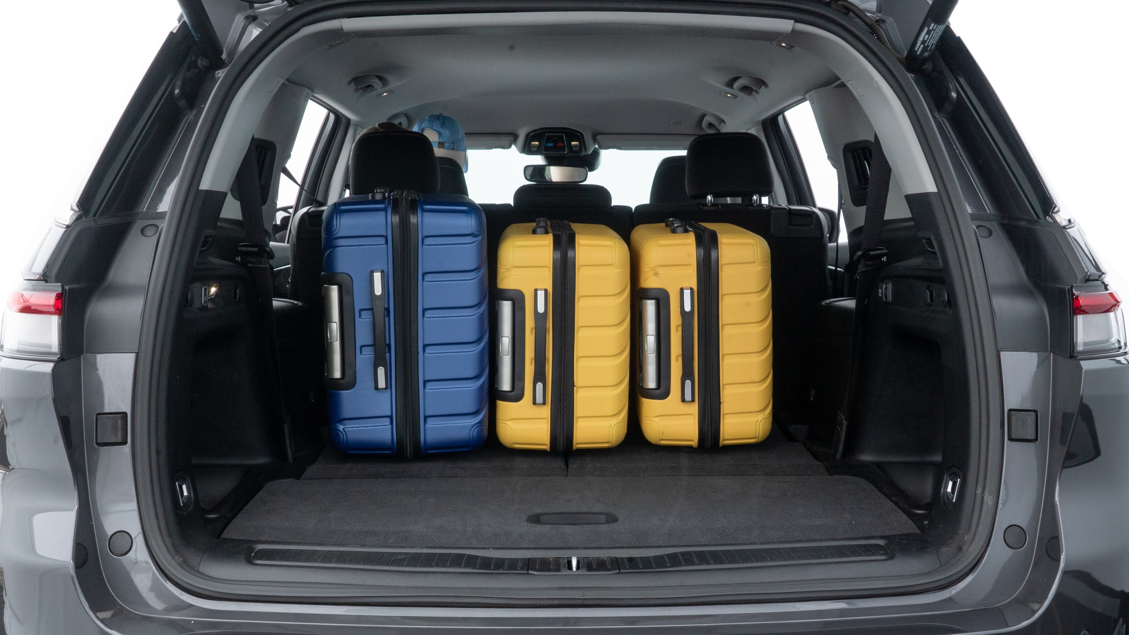The trunk lid is open, showing full view of the trunk space. One large, two medium, and two small suitcases are placed inside.