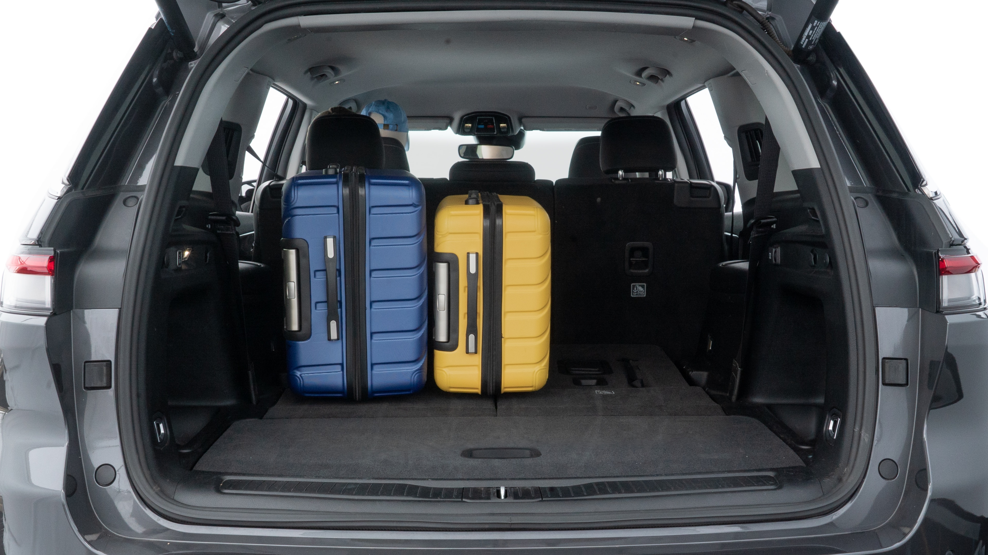 The trunk lid is open, showing full view of the trunk space. One large, two medium, and two small suitcases are placed inside.