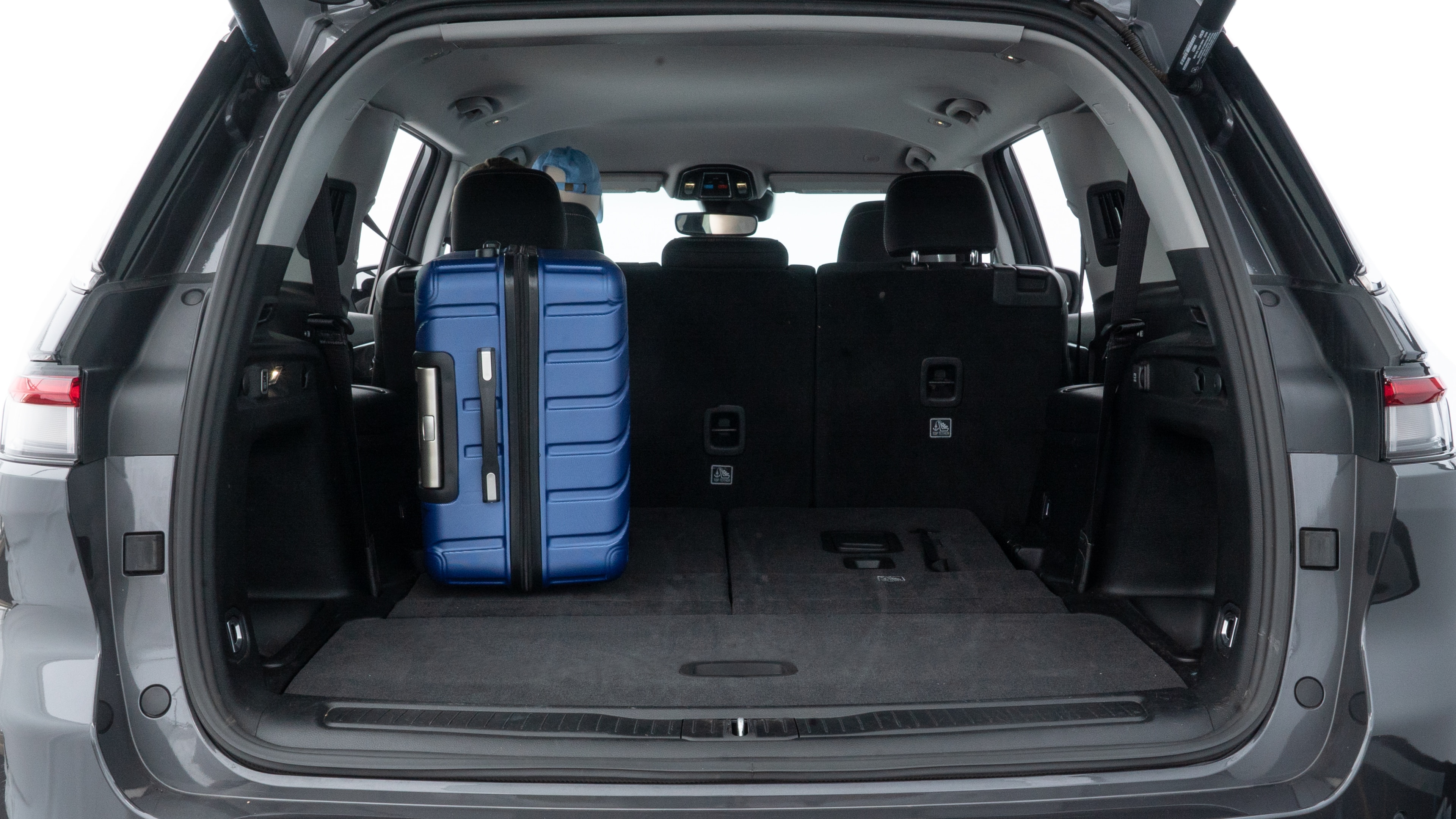 The trunk lid is open, showing full view of the trunk space. One large, two medium, and two small suitcases are placed inside.