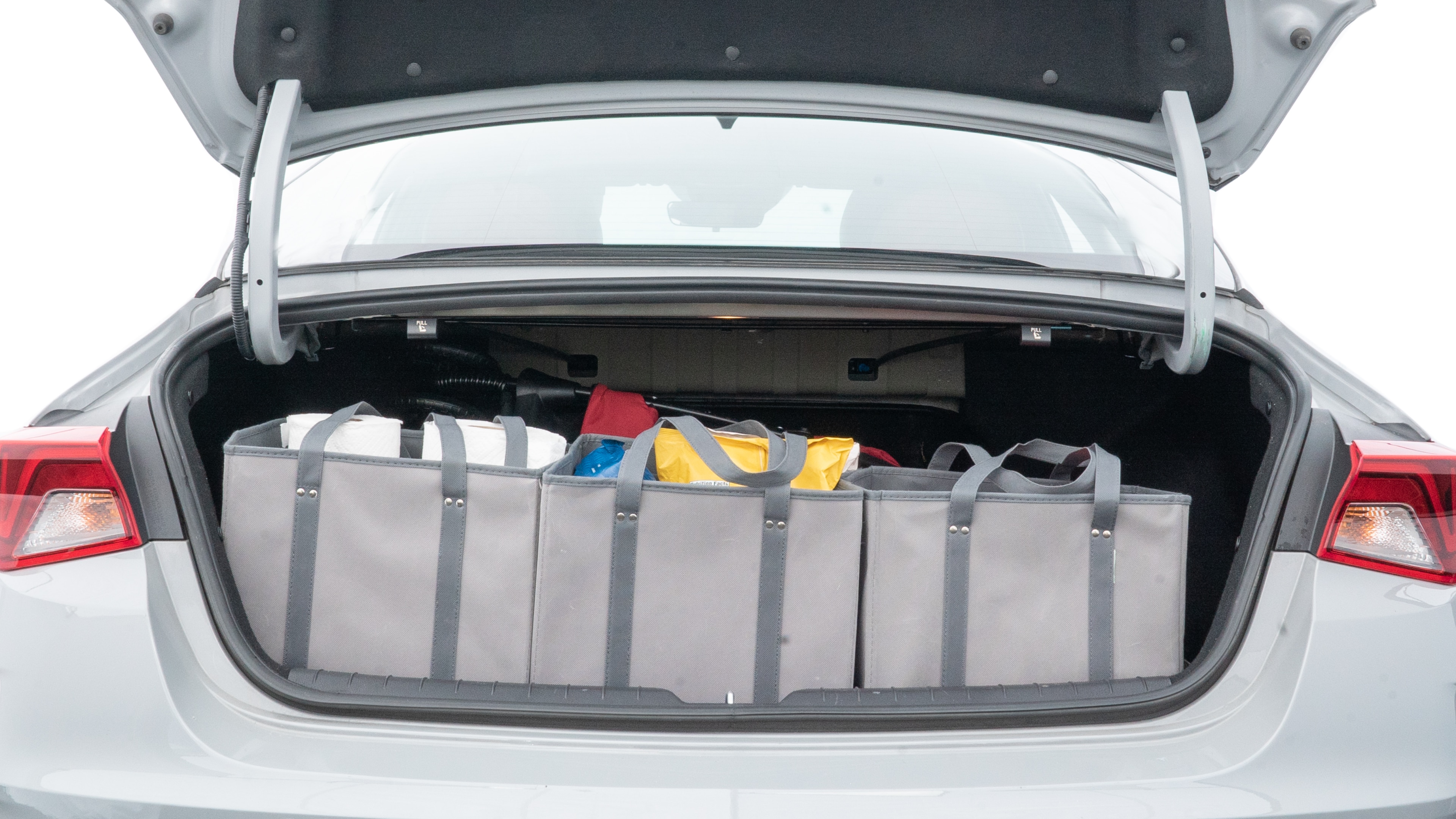 The trunk lid is open showing full view of the trunk. A baby stroller, three grocery carriers, two camping chairs in the carrying bag, and a set of golf clubs are placed inside.