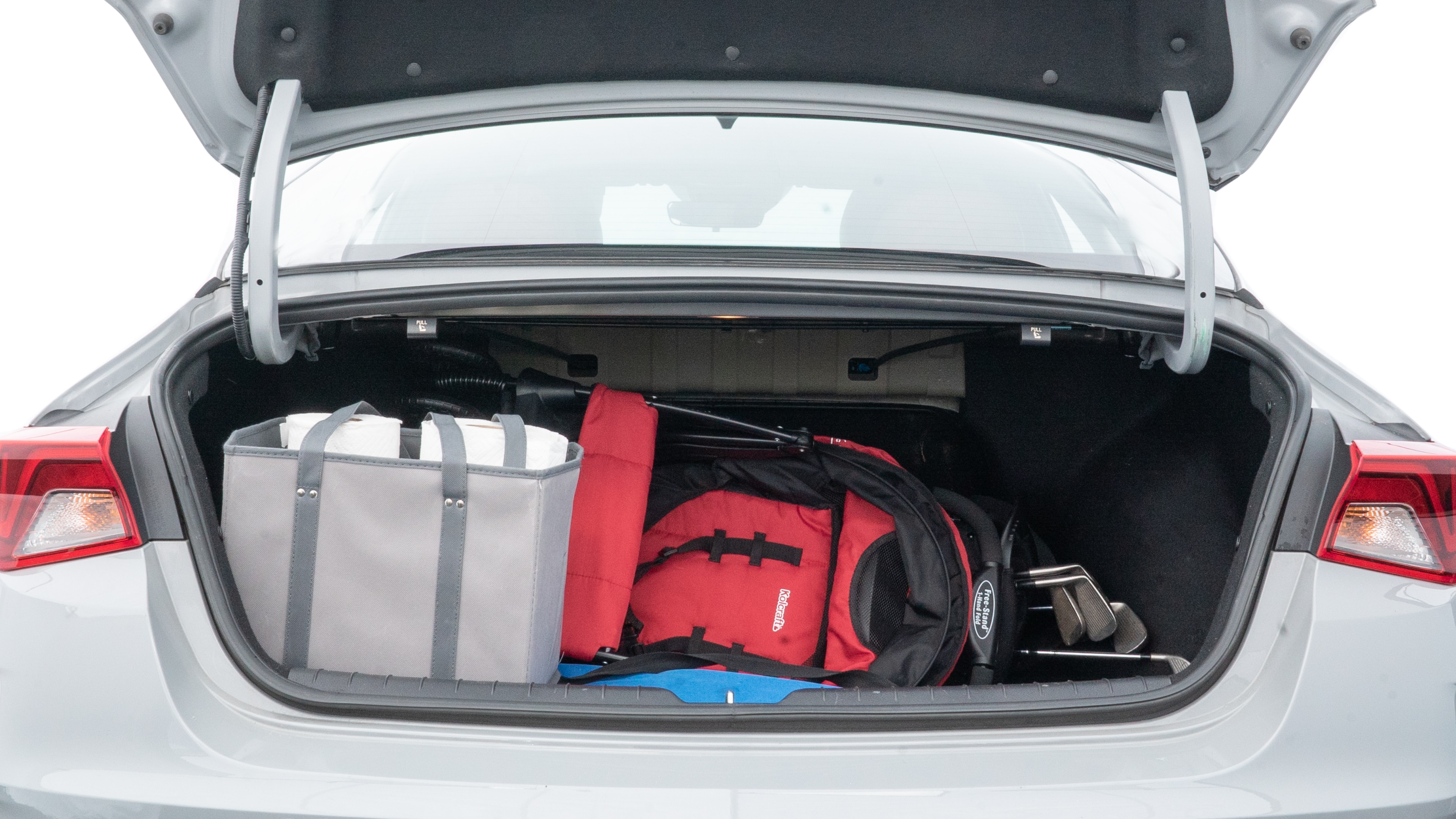 The trunk lid is open showing full view of the trunk. A baby stroller, three grocery carriers, two camping chairs in the carrying bag, and a set of golf clubs are placed inside.