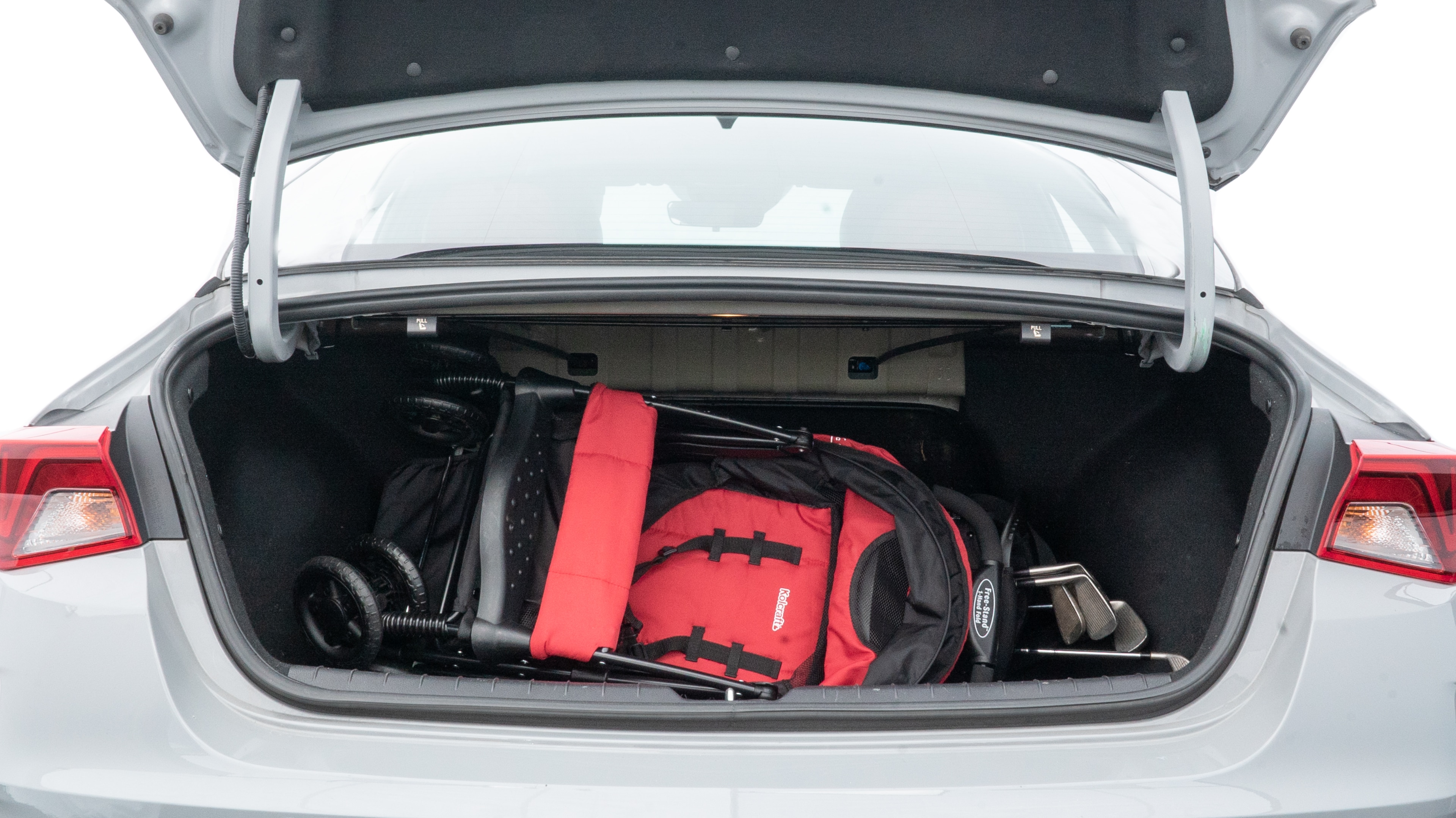 The trunk lid is open showing full view of the trunk. A baby stroller, three grocery carriers, two camping chairs in the carrying bag, and a set of golf clubs are placed inside.