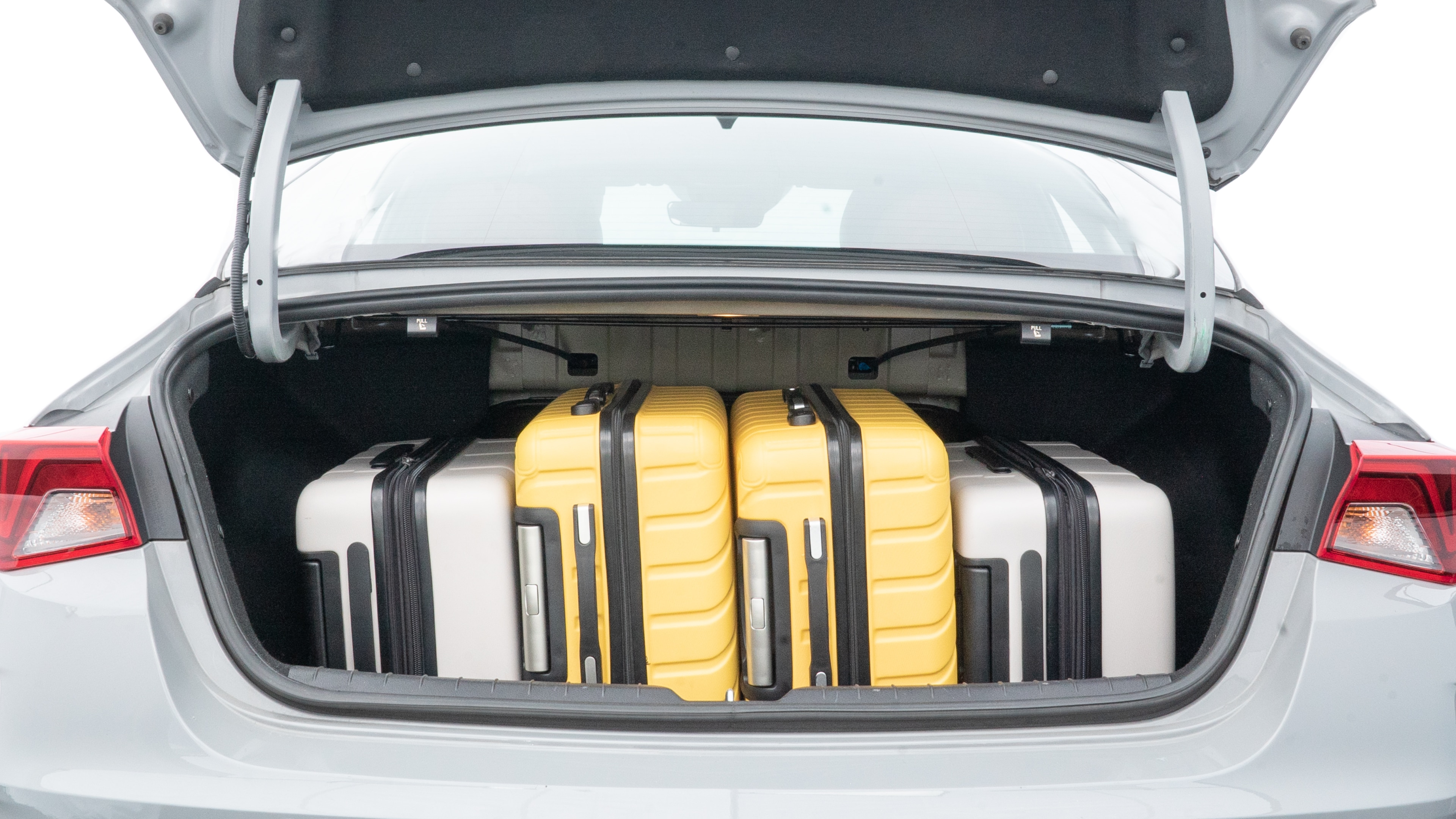 The trunk lid is open, showing full view of the trunk space. Two medium and two small suitcases are placed inside.