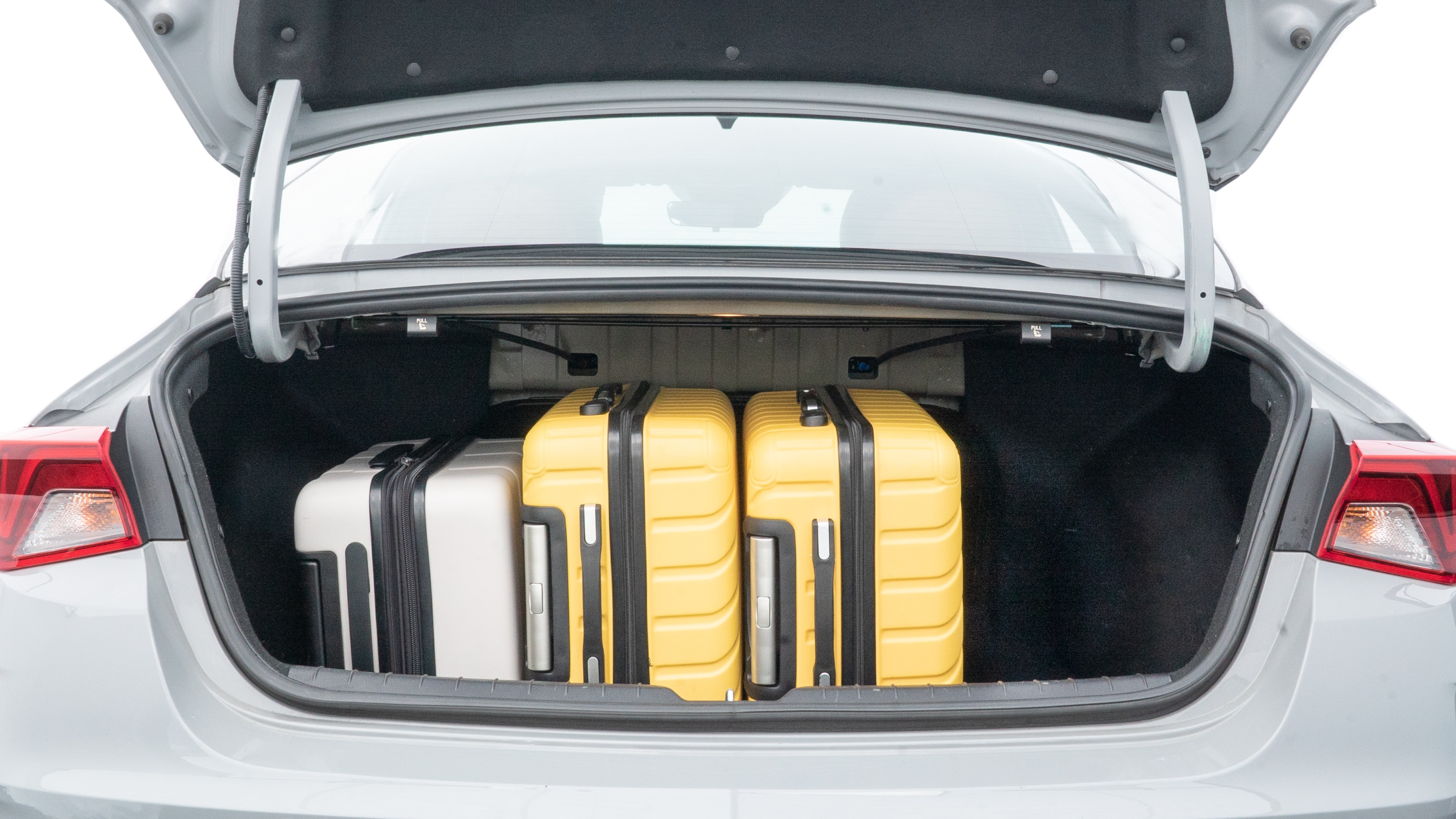 The trunk lid is open, showing full view of the trunk space. Two medium and two small suitcases are placed inside.