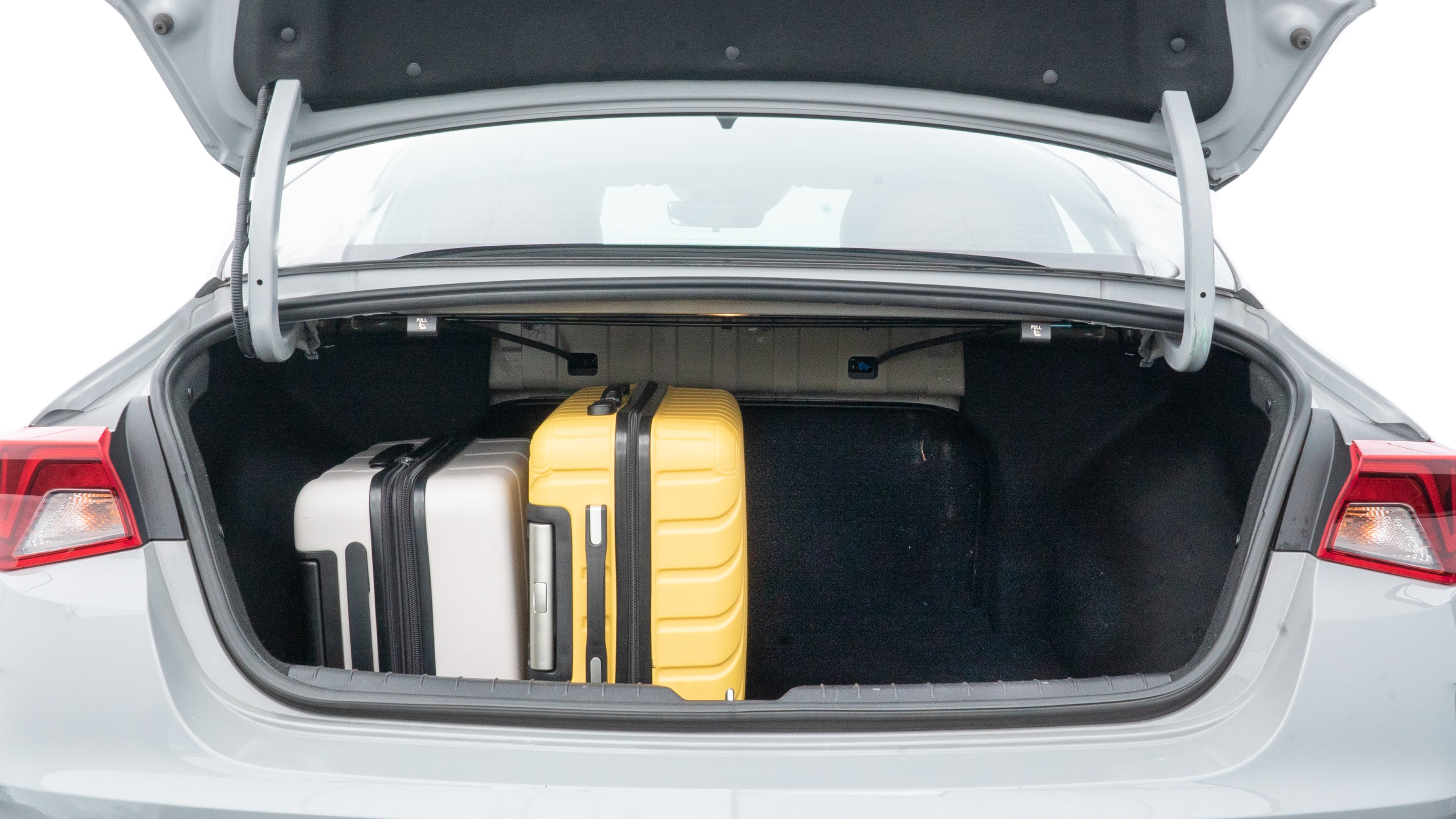 The trunk lid is open, showing full view of the trunk space. Two medium and two small suitcases are placed inside.