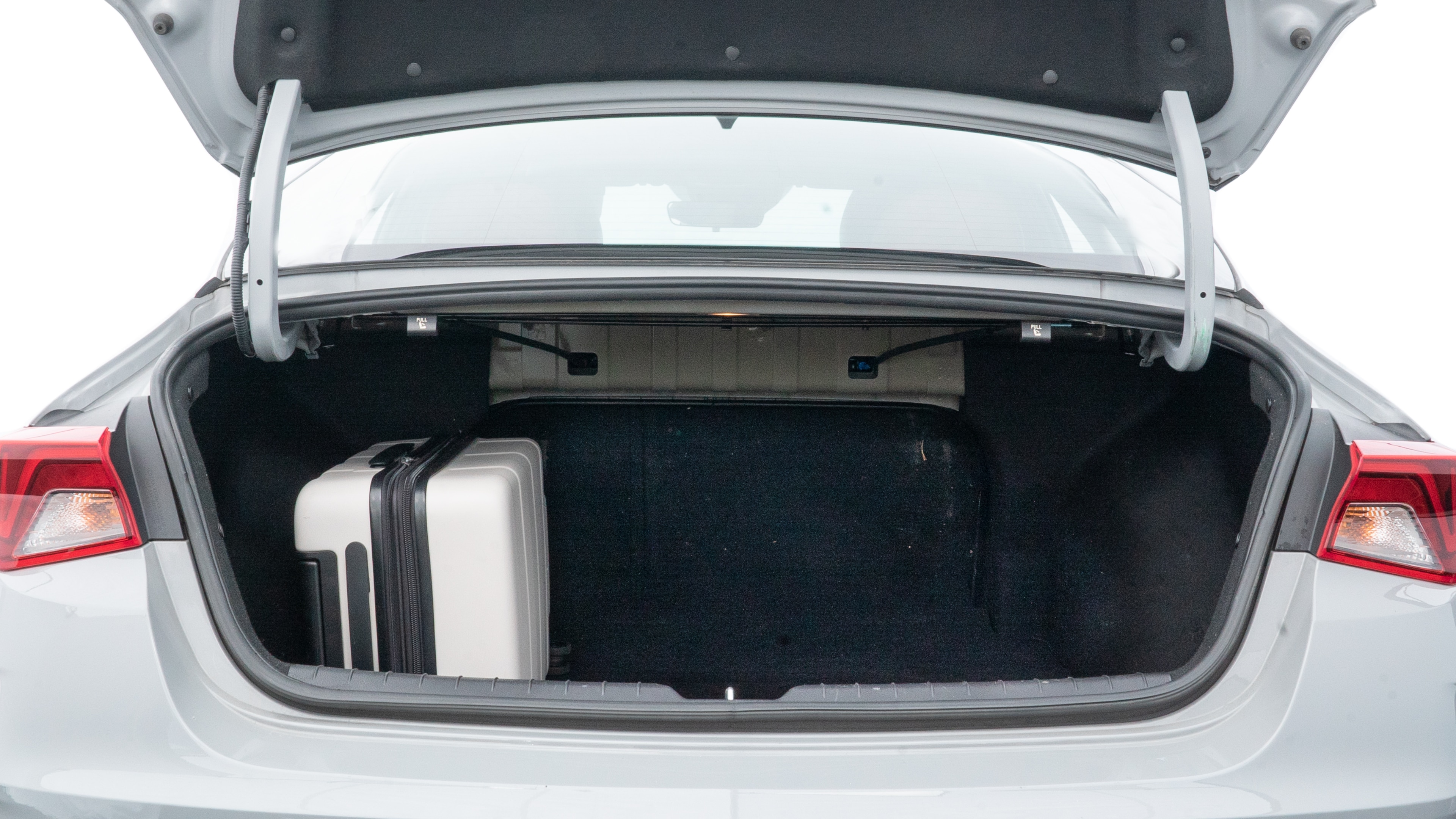 The trunk lid is open, showing full view of the trunk space. Two medium and two small suitcases are placed inside.