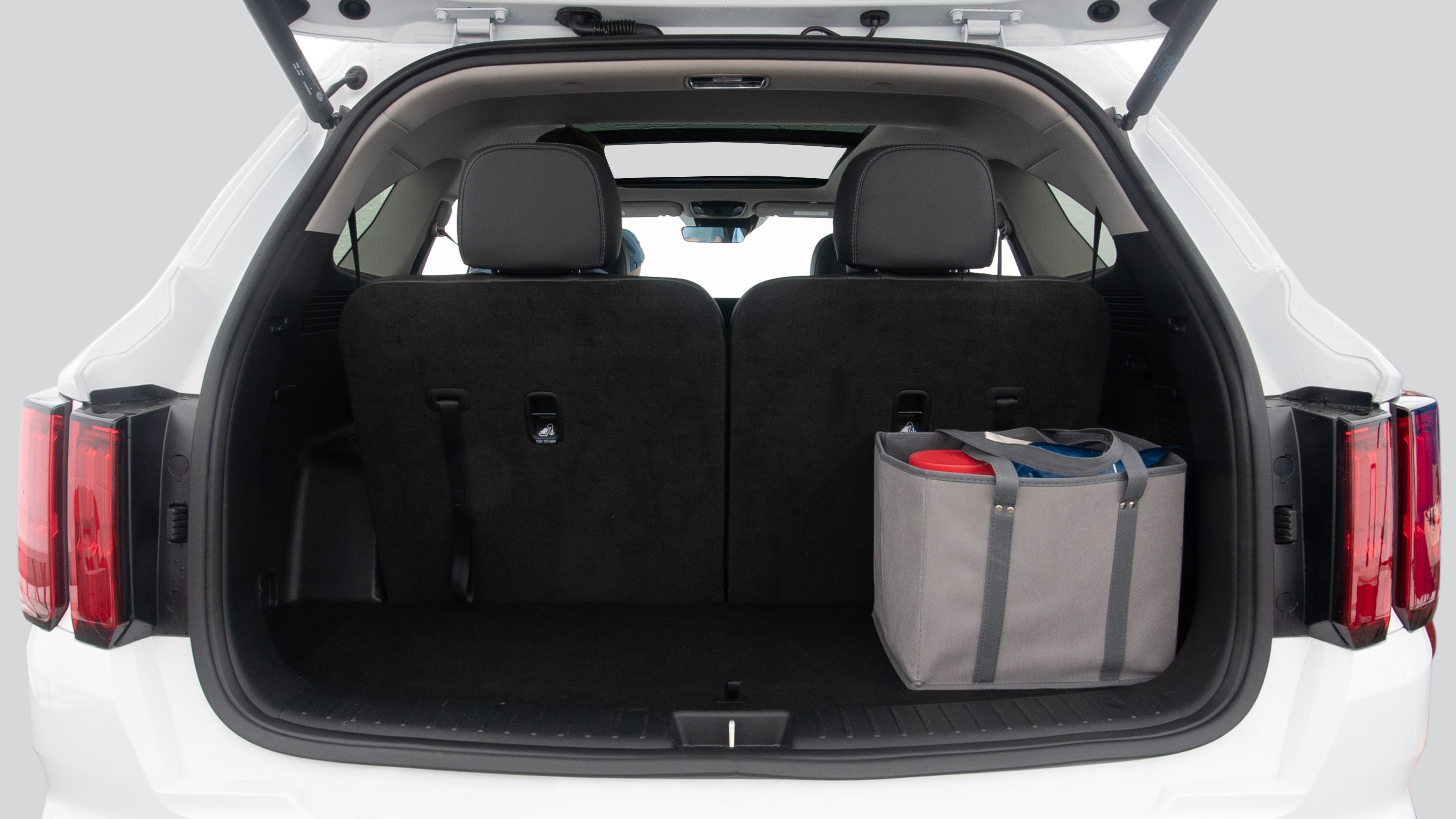 The trunk lid is open showing full view of the trunk. Three grocery carriers, and two camping chairs in the carrying bag are placed inside.