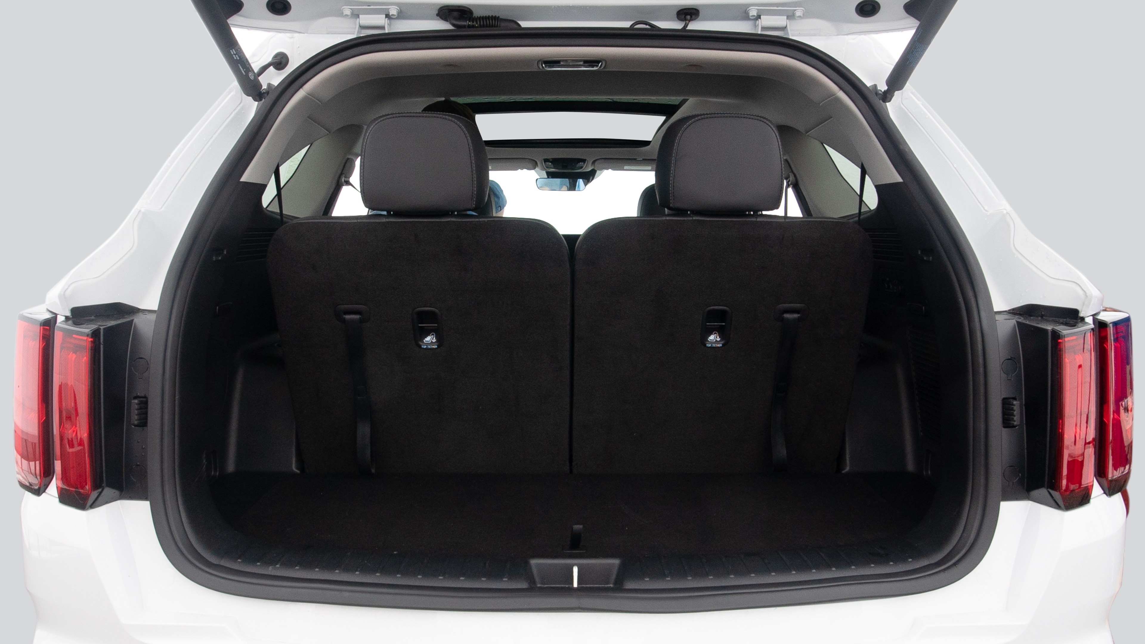 The trunk lid is open showing full view of the trunk. Three grocery carriers, and two camping chairs in the carrying bag are placed inside.