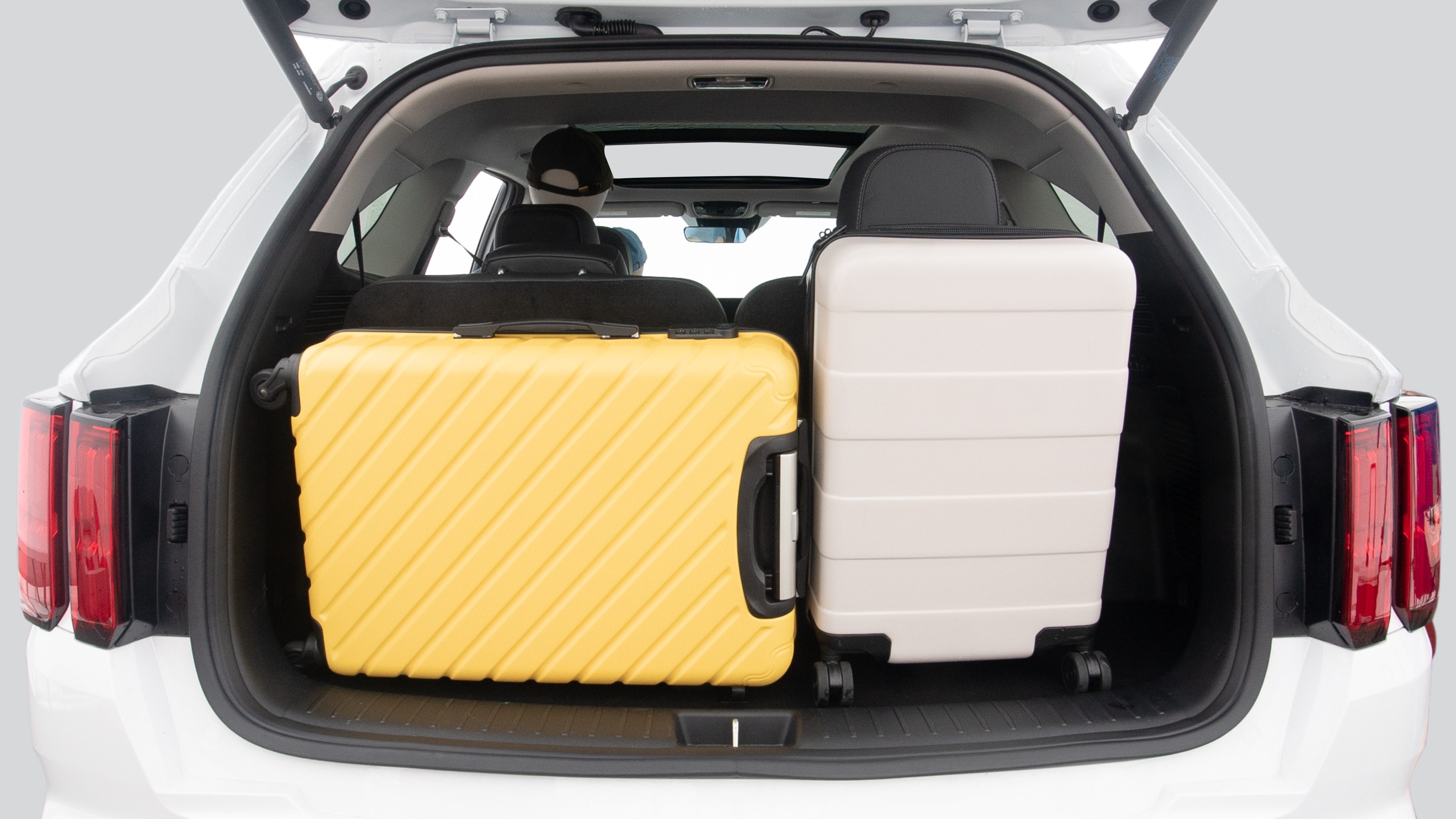 The trunk lid is open, showing full view of the trunk space. Two suitcases, one large and one small suitcase are placed inside.