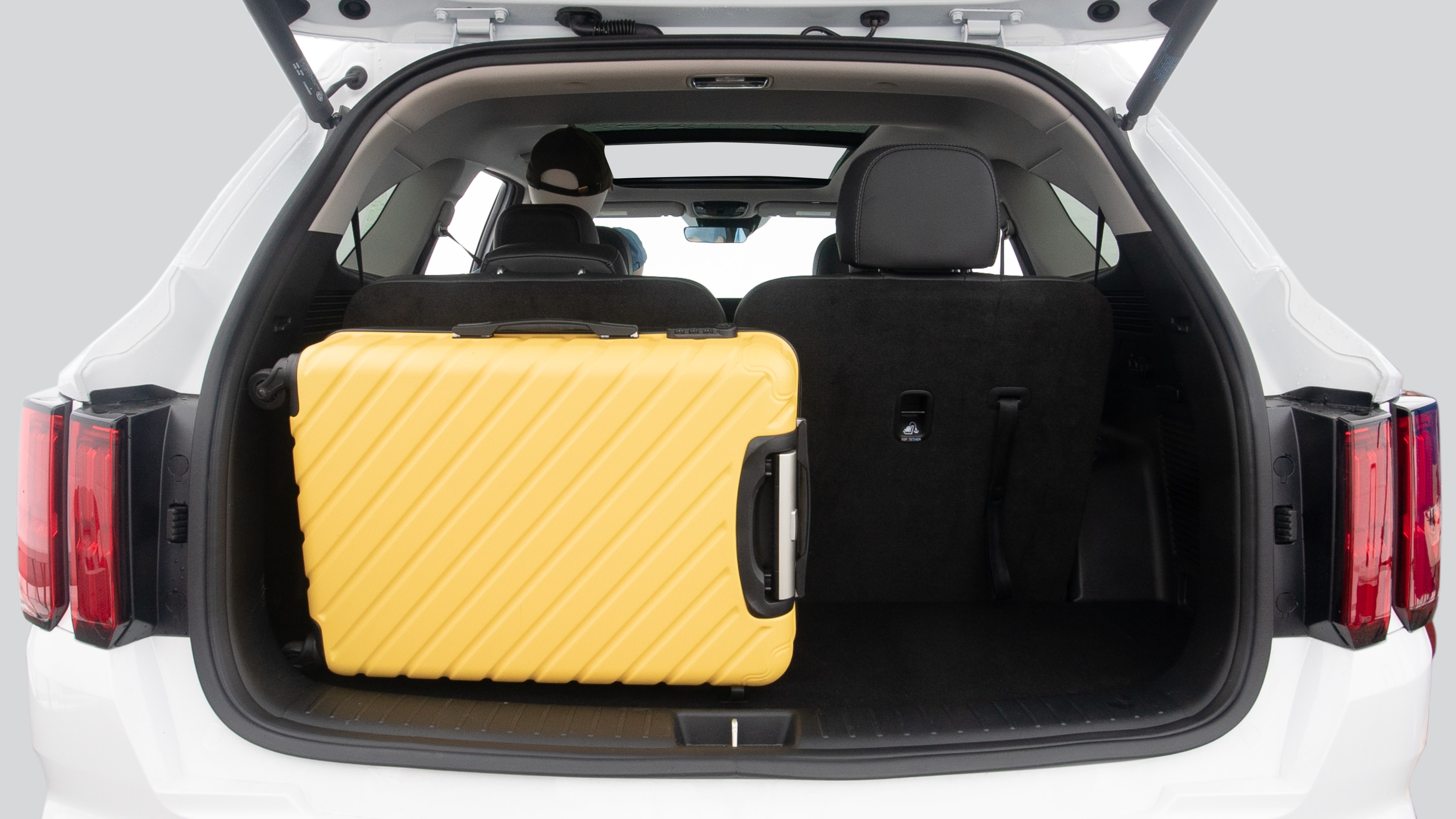 The trunk lid is open, showing full view of the trunk space. Two suitcases, one large and one small suitcase are placed inside.