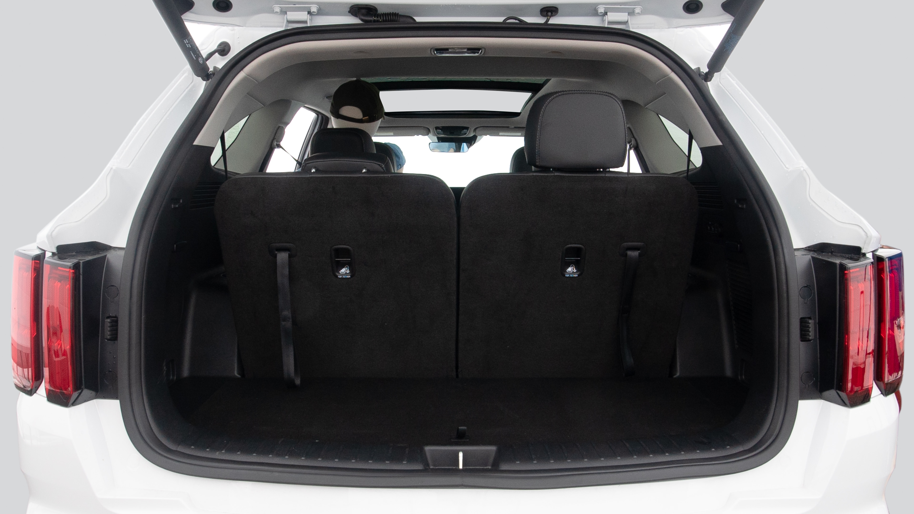 The trunk lid is open, showing full view of the trunk space. Two suitcases, one large and one small suitcase are placed inside.