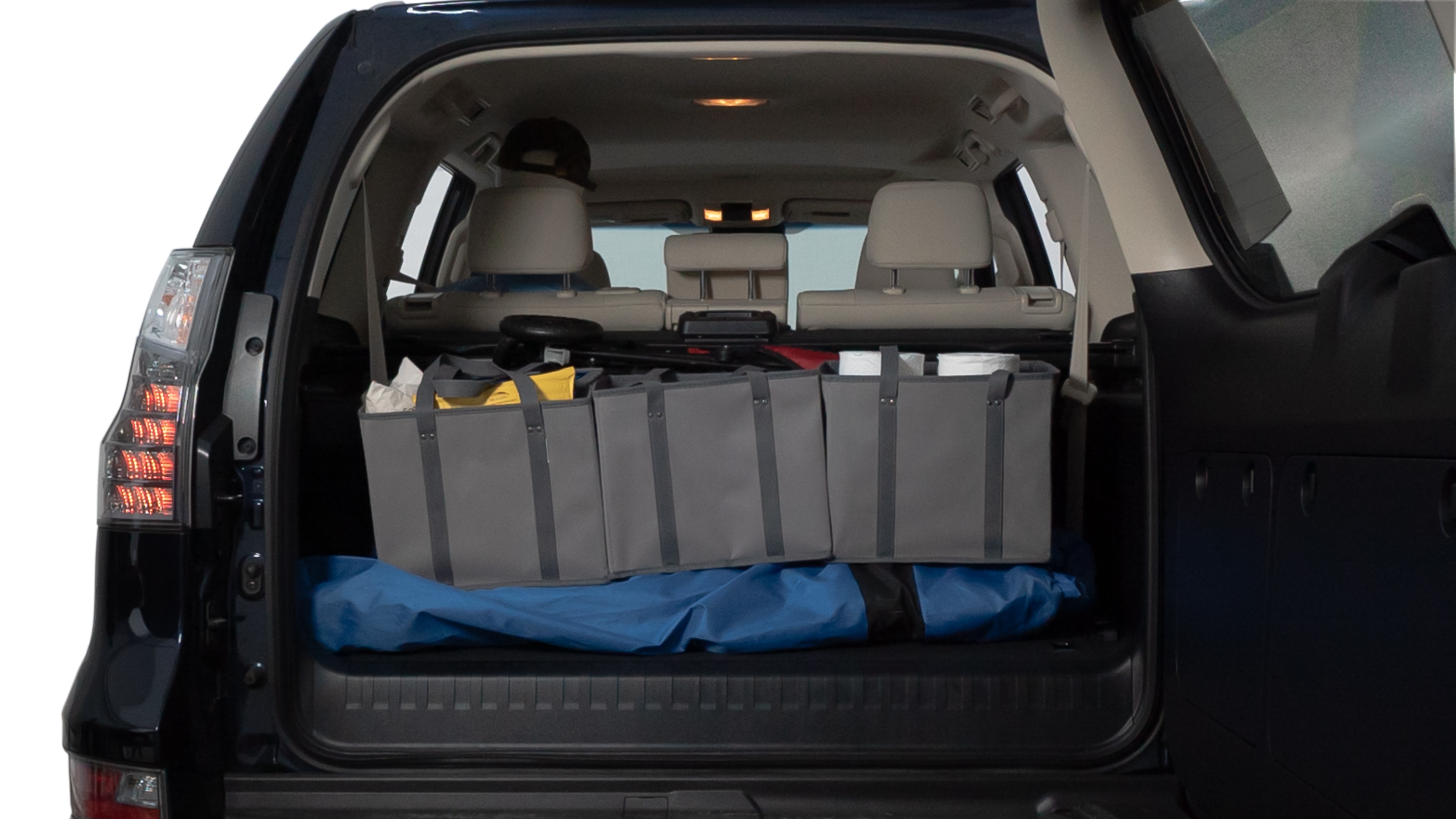 The trunk lid is open showing full view of the trunk. A baby stroller, three grocery carriers, two camping chairs in the carrying bag, and a set of golf clubs are placed inside.