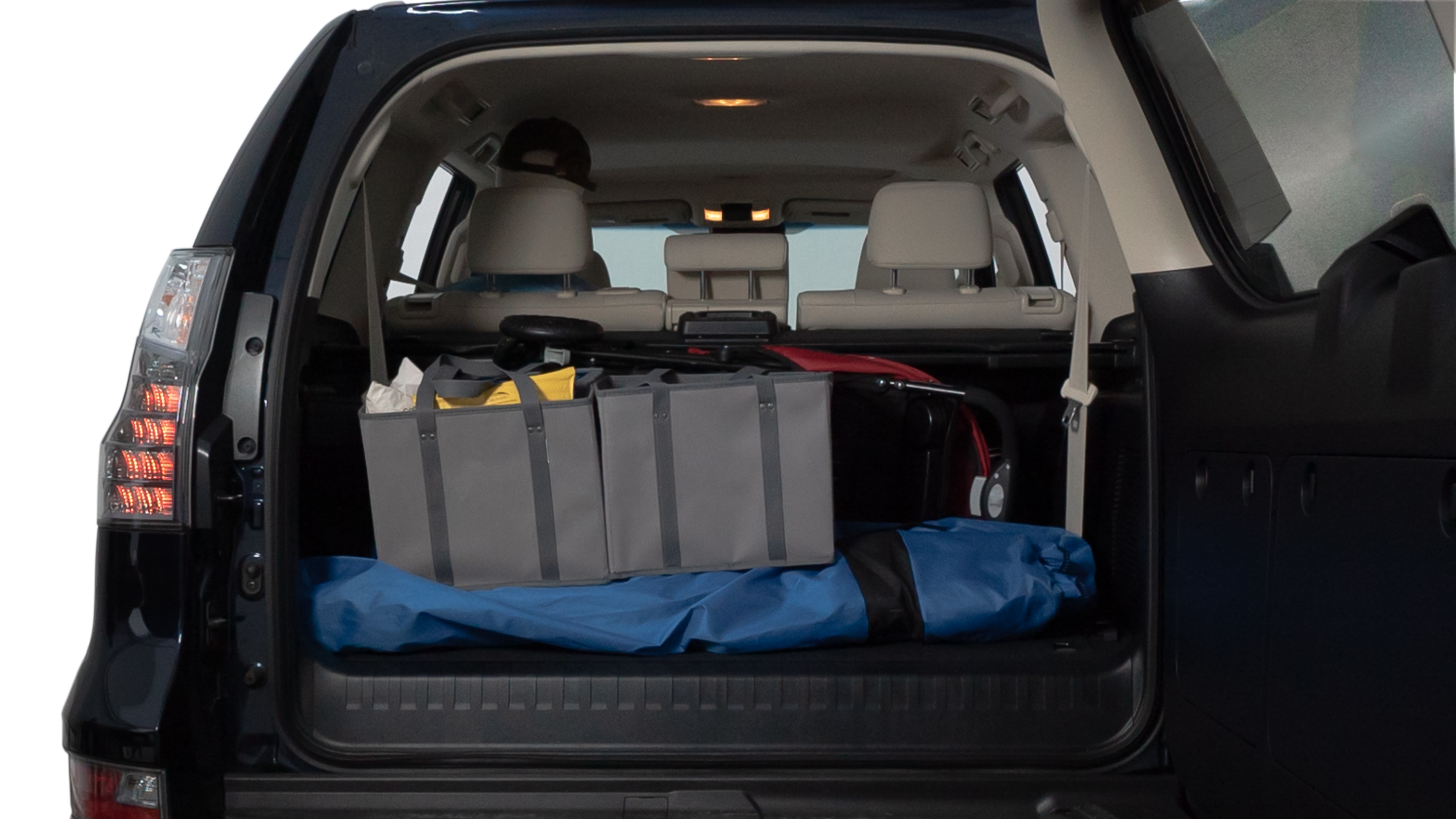 The trunk lid is open showing full view of the trunk. A baby stroller, three grocery carriers, two camping chairs in the carrying bag, and a set of golf clubs are placed inside.