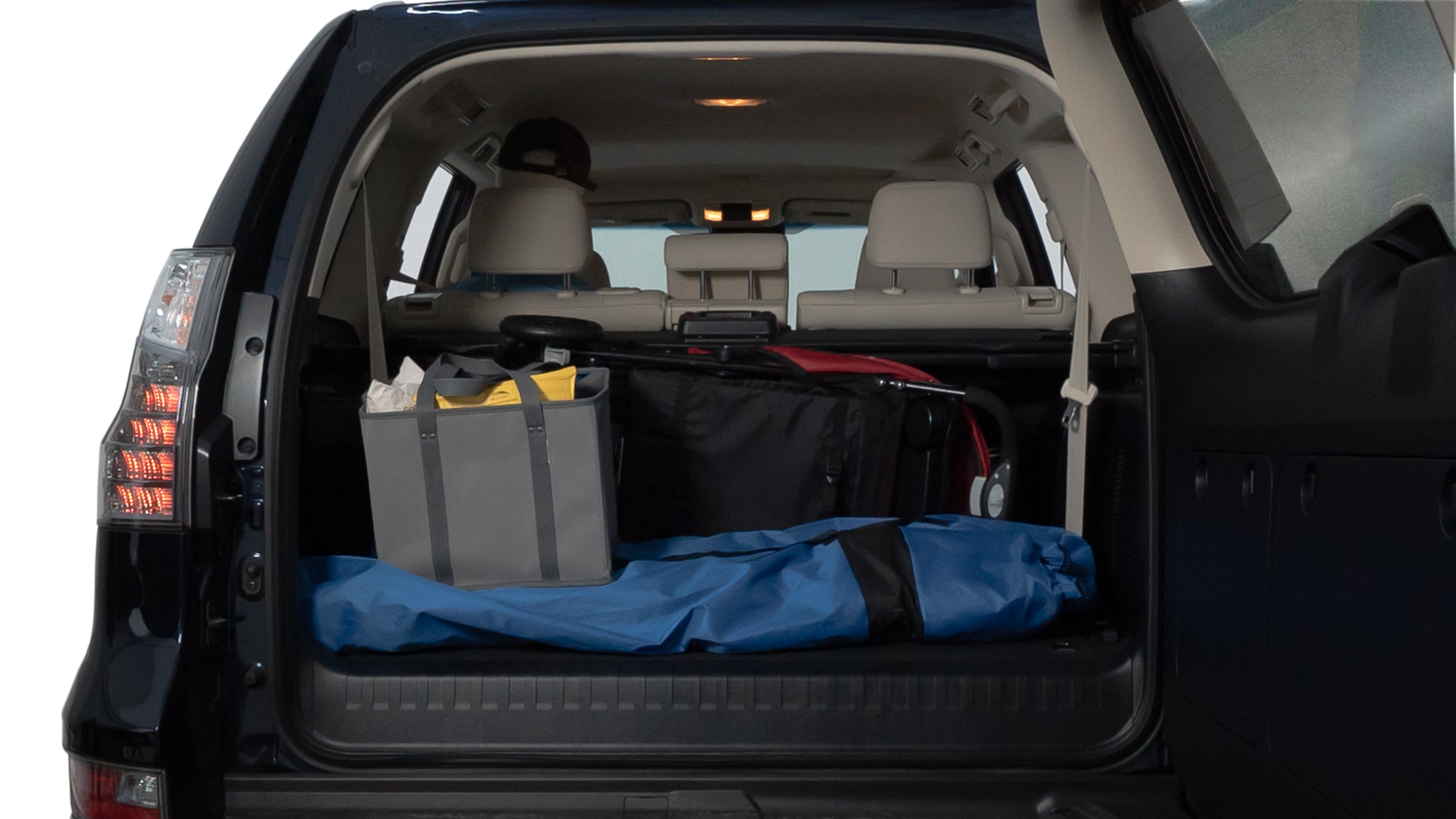The trunk lid is open showing full view of the trunk. A baby stroller, three grocery carriers, two camping chairs in the carrying bag, and a set of golf clubs are placed inside.