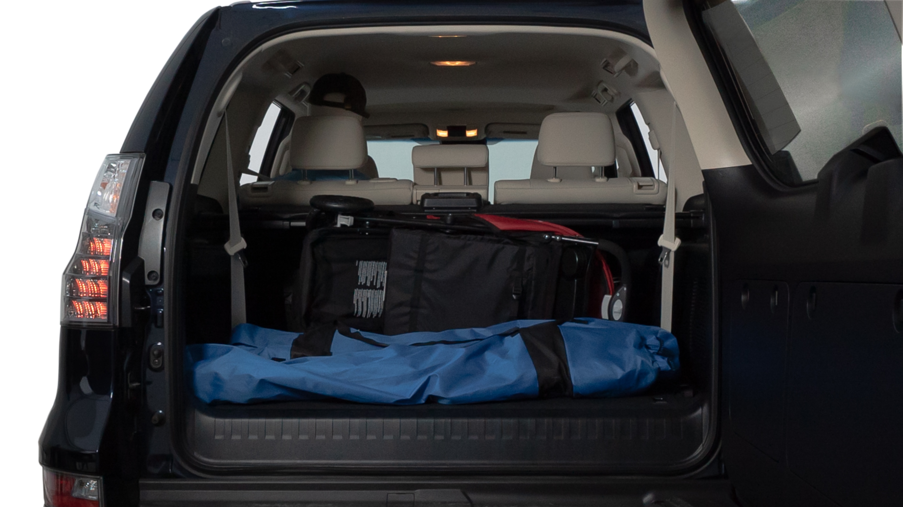 The trunk lid is open showing full view of the trunk. A baby stroller, three grocery carriers, two camping chairs in the carrying bag, and a set of golf clubs are placed inside.