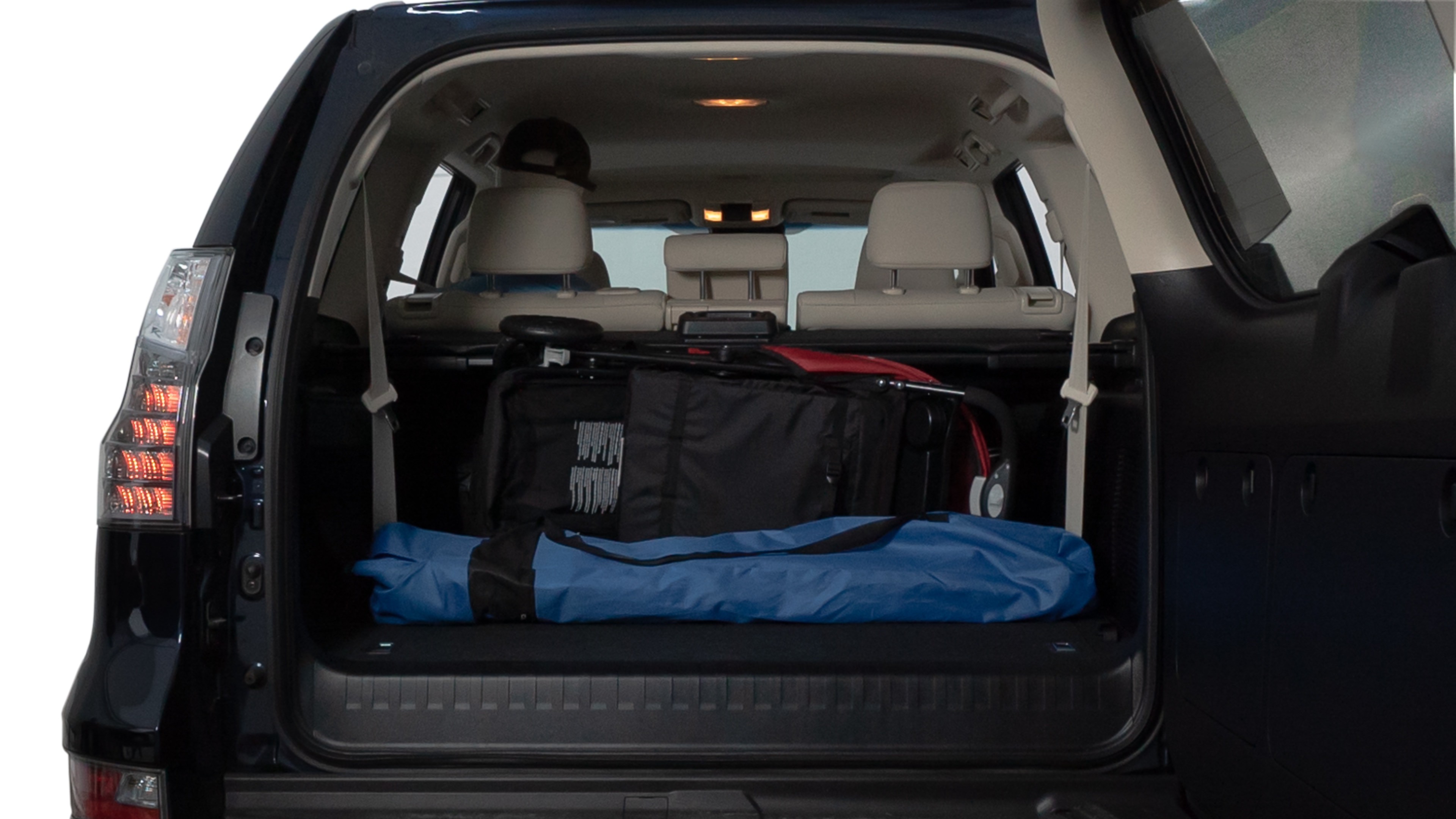 The trunk lid is open showing full view of the trunk. A baby stroller, three grocery carriers, two camping chairs in the carrying bag, and a set of golf clubs are placed inside.